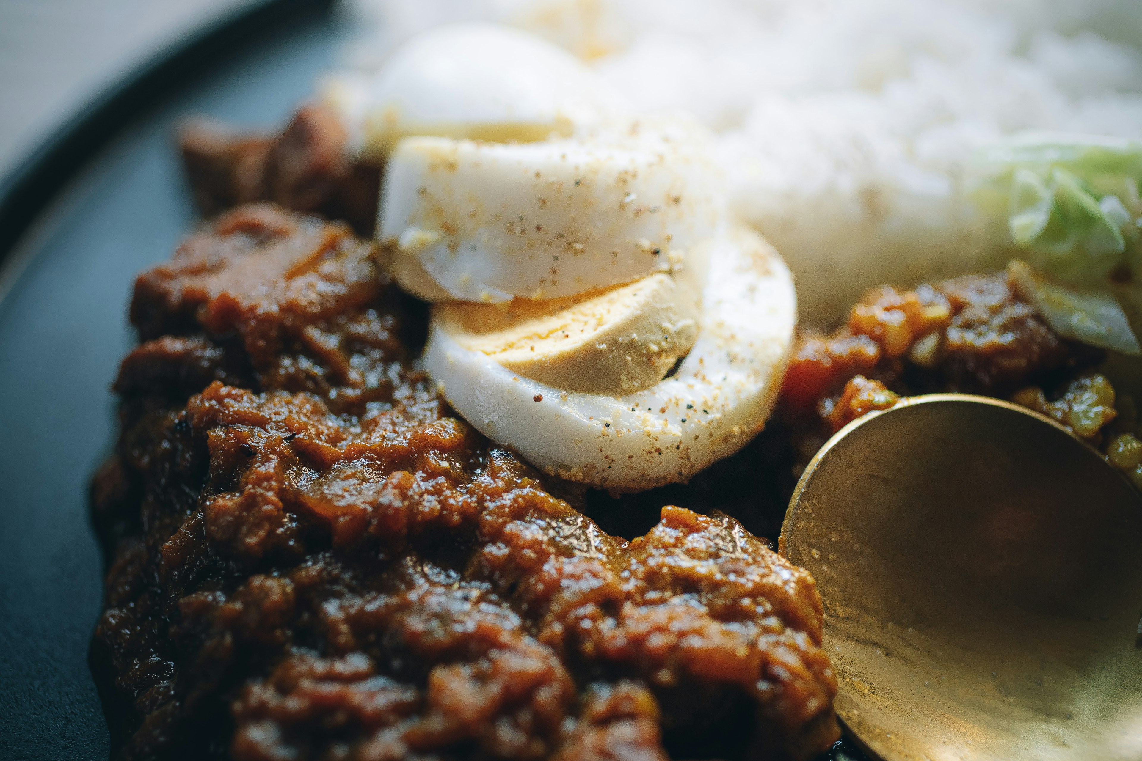 Une assiette de riz avec un plat de viande épicée et des tranches d'œufs joliment garnies