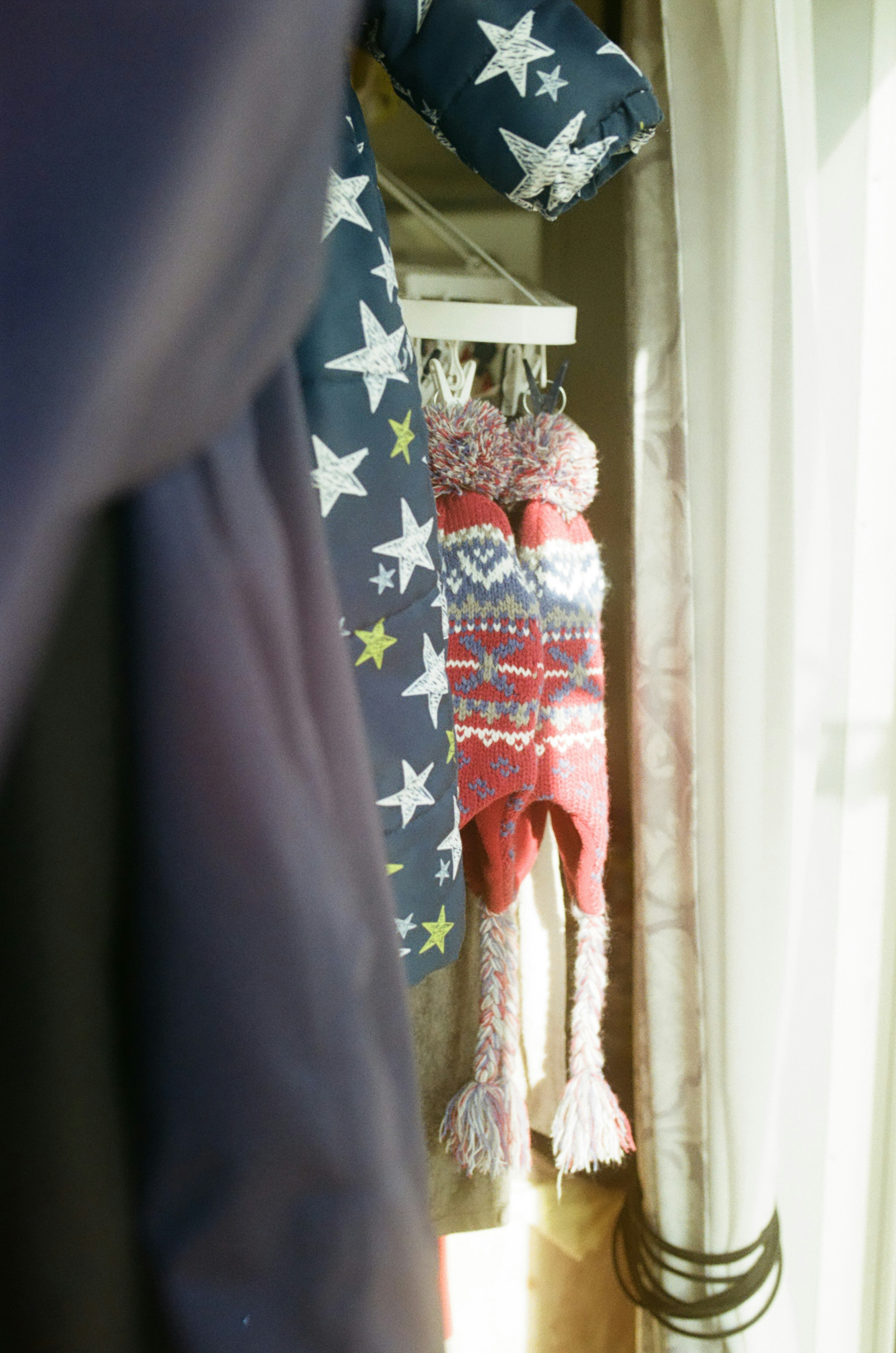 A view of star-patterned clothing and a colorful knitted hat hanging