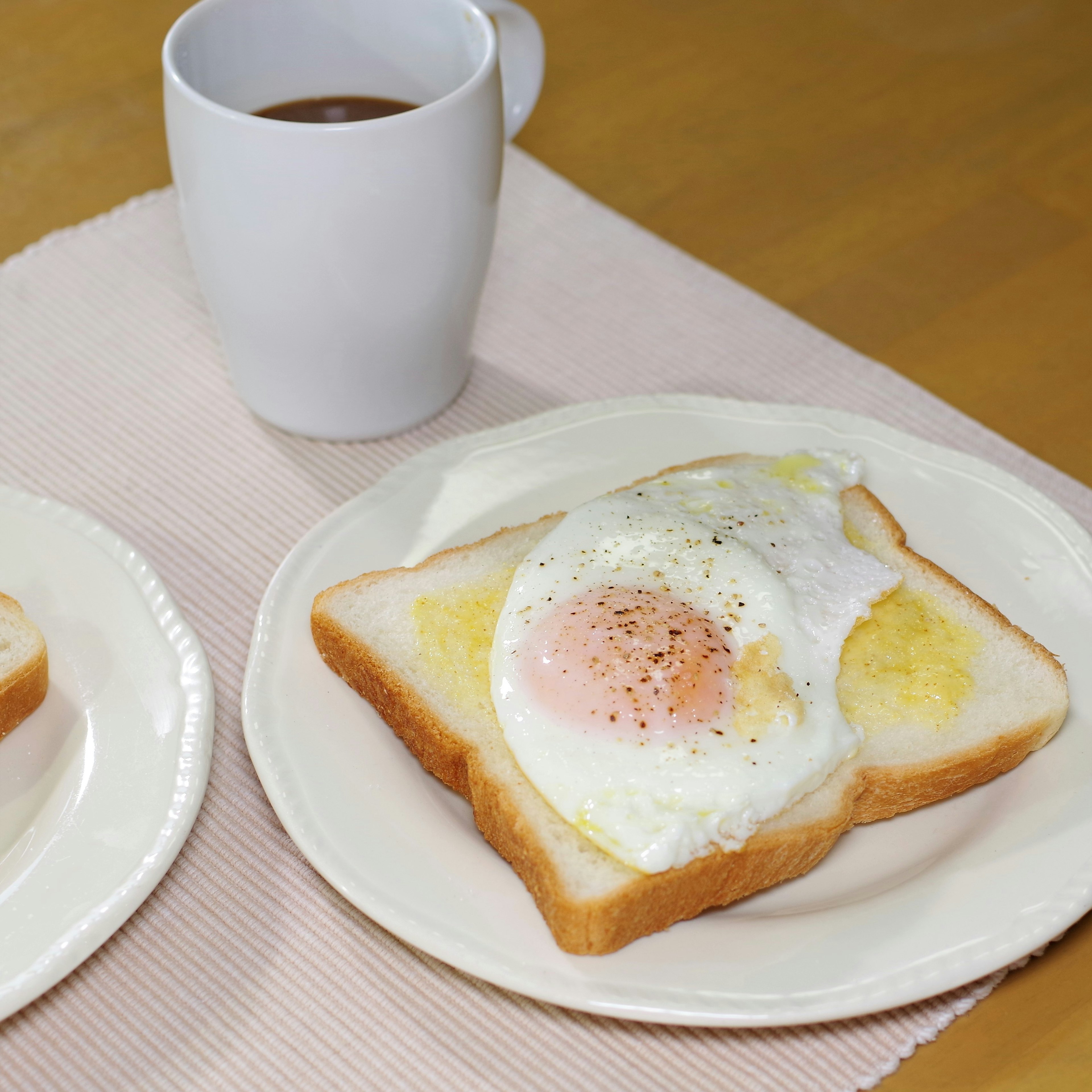 Piatto per colazione con toast guarnito con un uovo fritto e una tazza di caffè