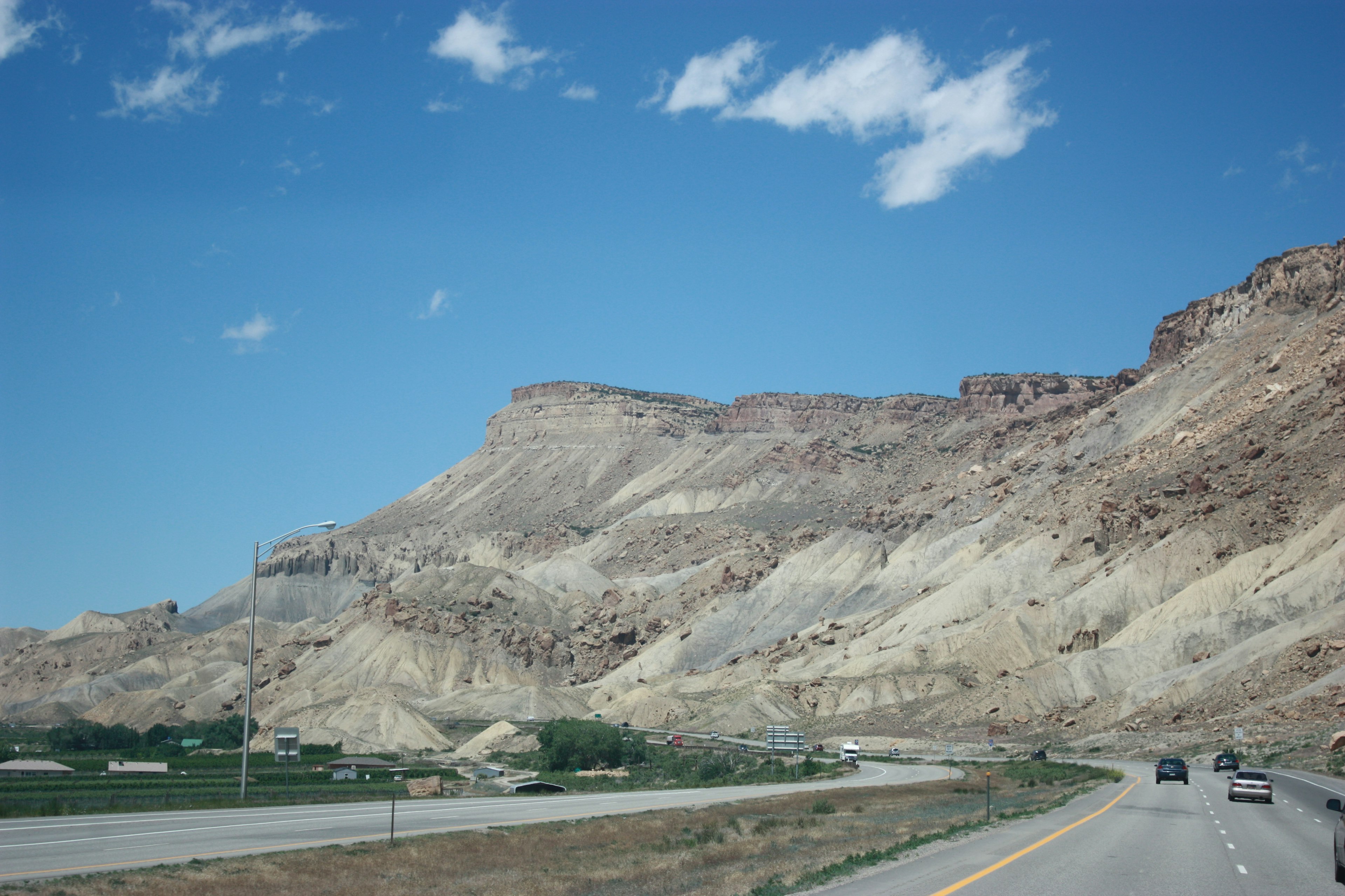 Landscape of rocky cliffs under a blue sky with a highway