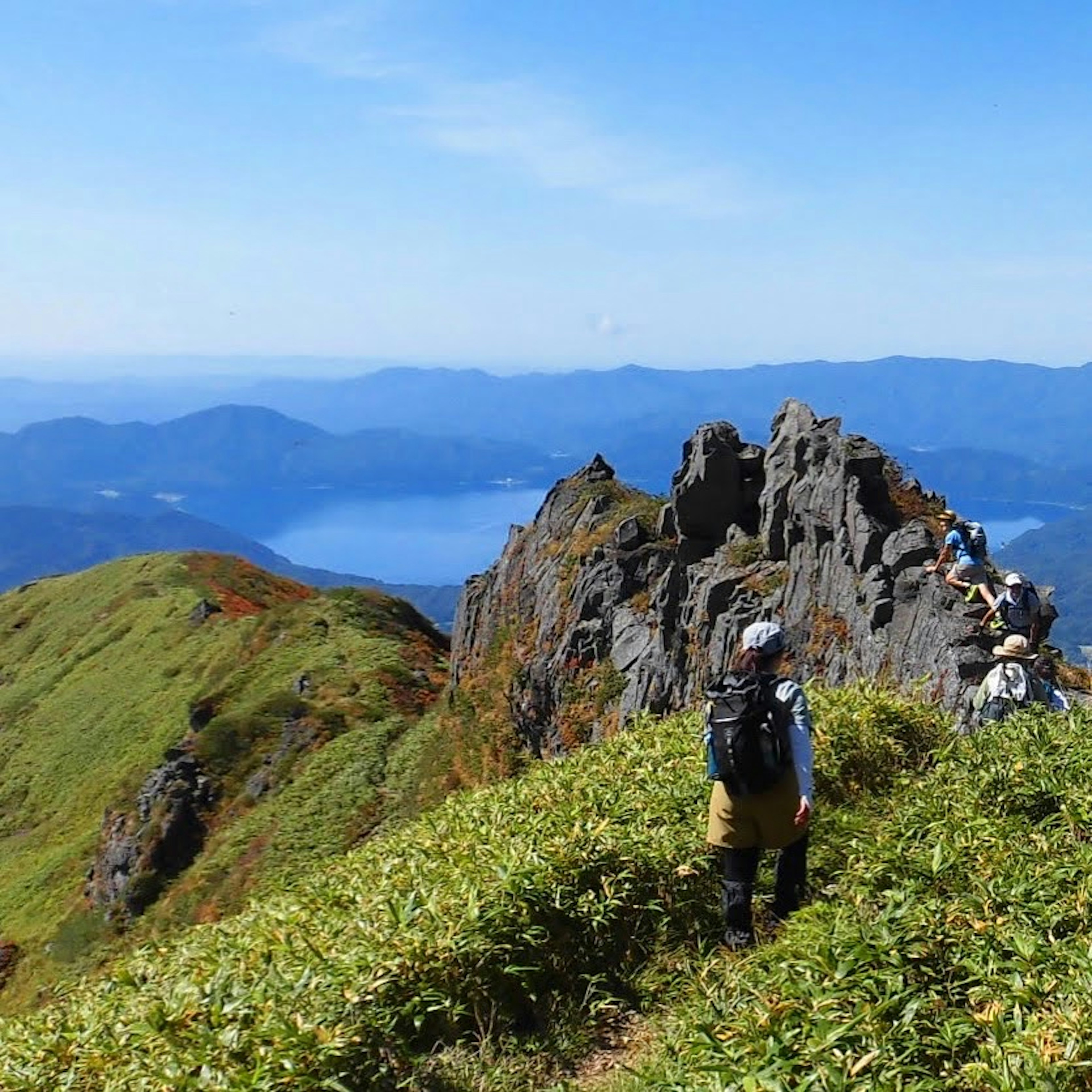 緑の山々と岩場を背景にハイキングを楽しむ人々