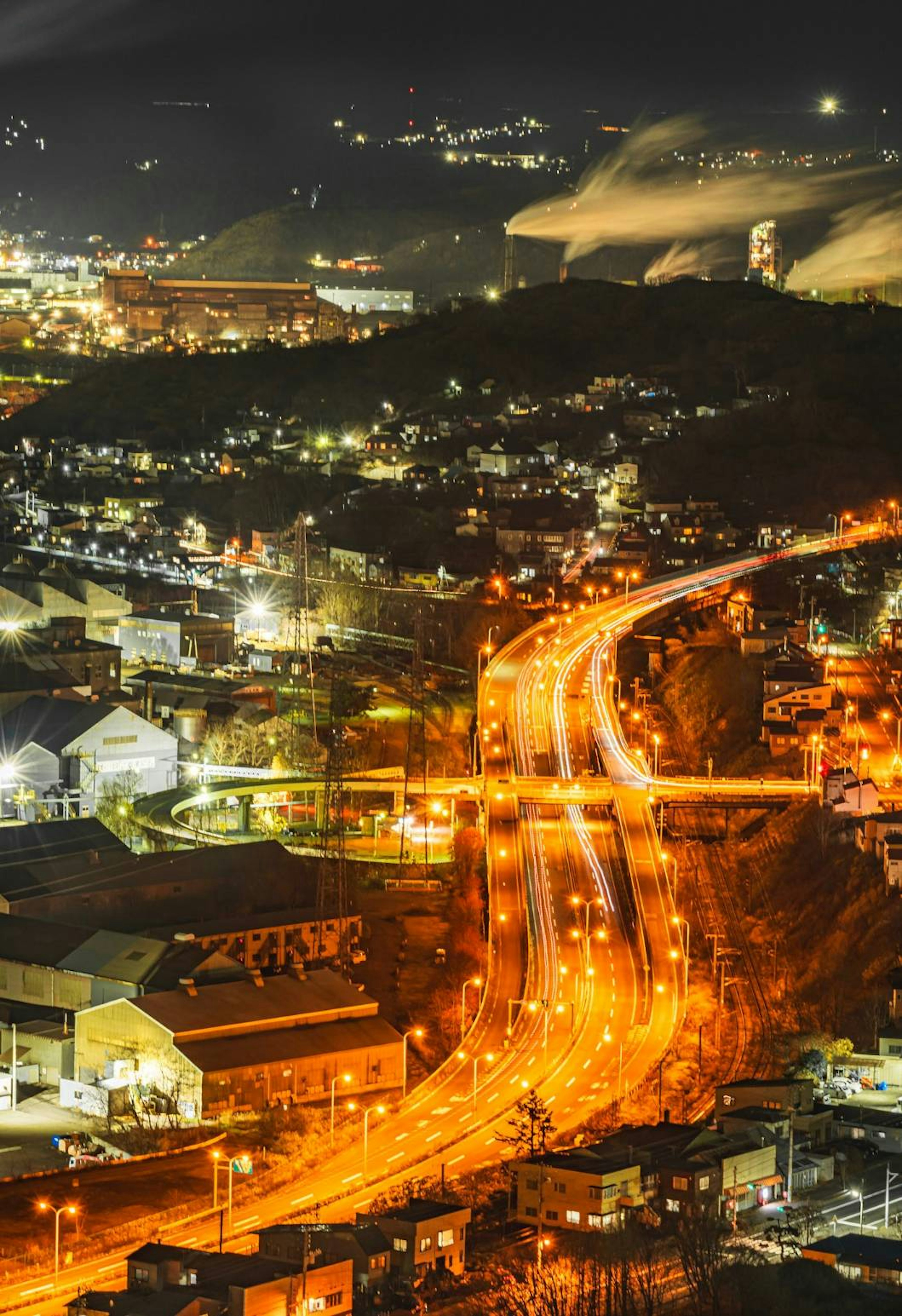 Vista nocturna de un paisaje urbano con carreteras iluminadas y sinuosas