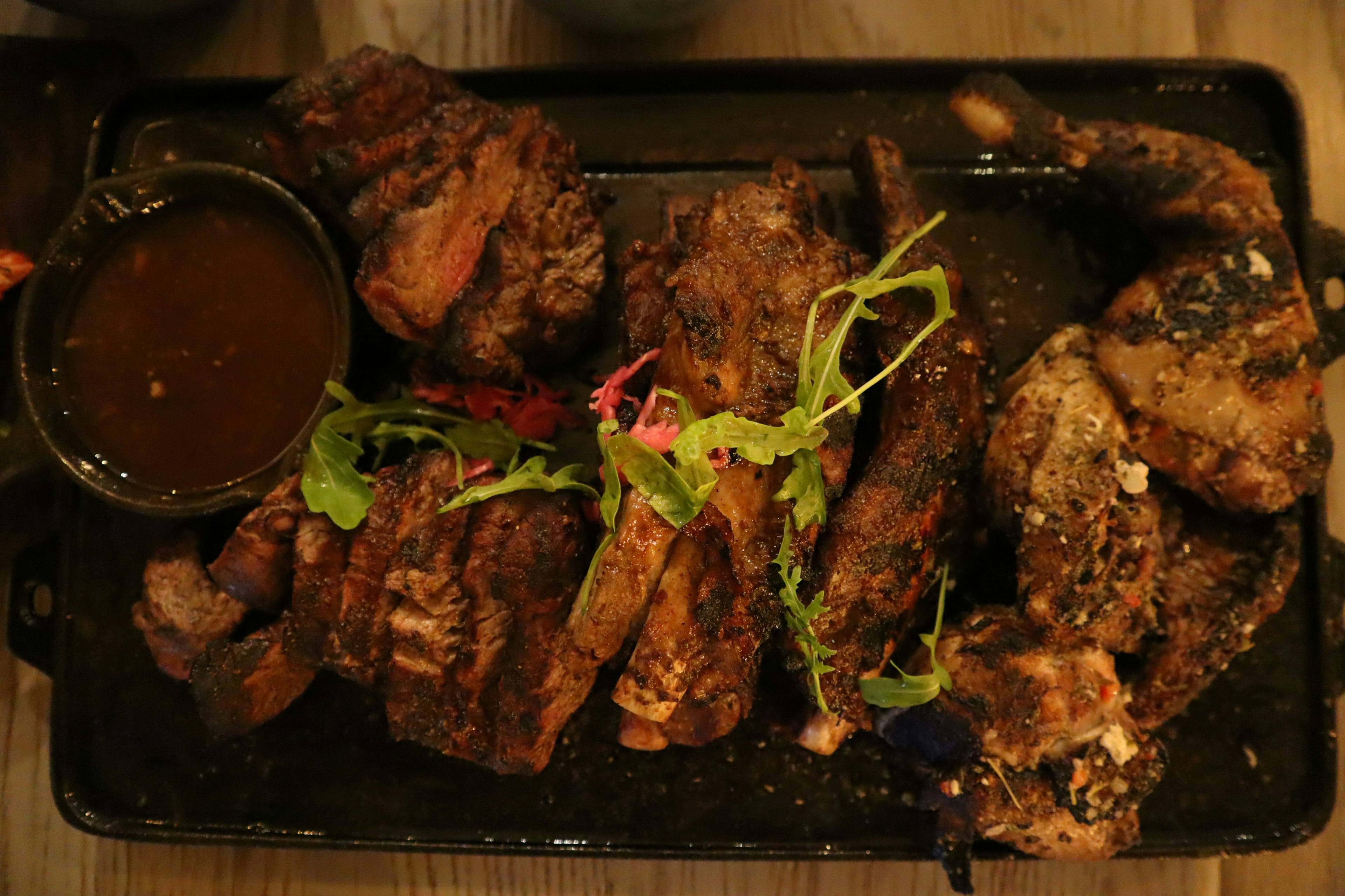 Platter of grilled meats with sauce and garnishes