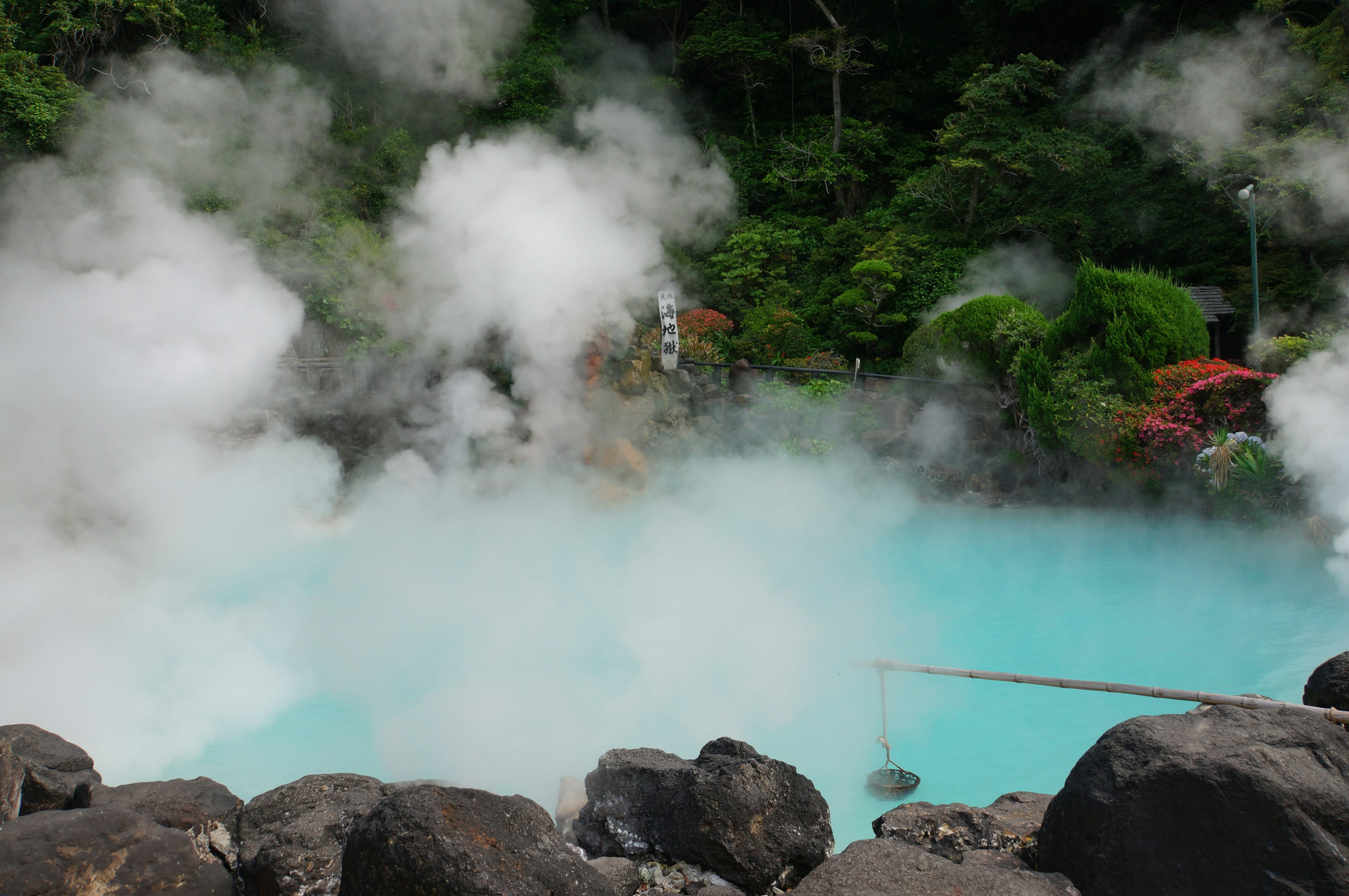 Sorgente termale blu con vapore che sale in un paesaggio naturale