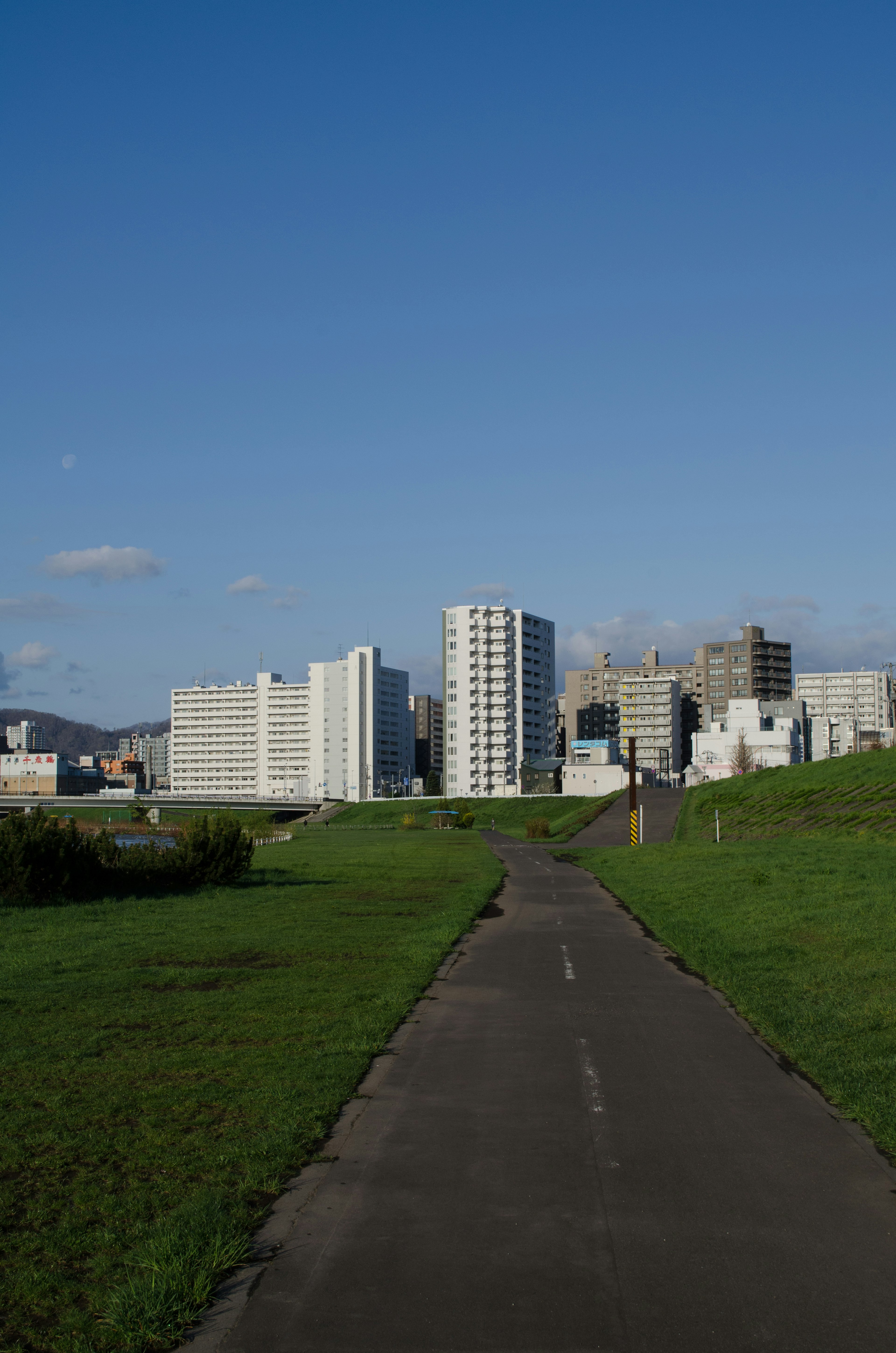 Edificios altos bajo un cielo azul con un parque verde