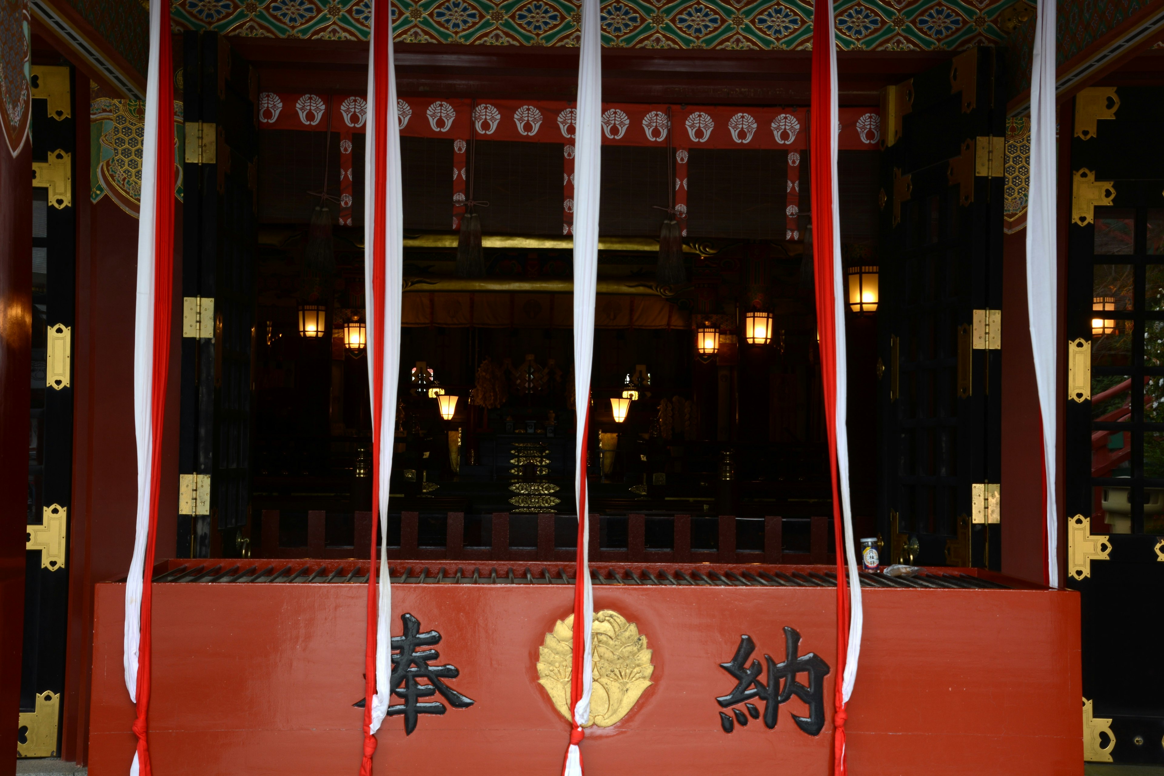 Entrance of a traditional Japanese building with red decorations and golden details