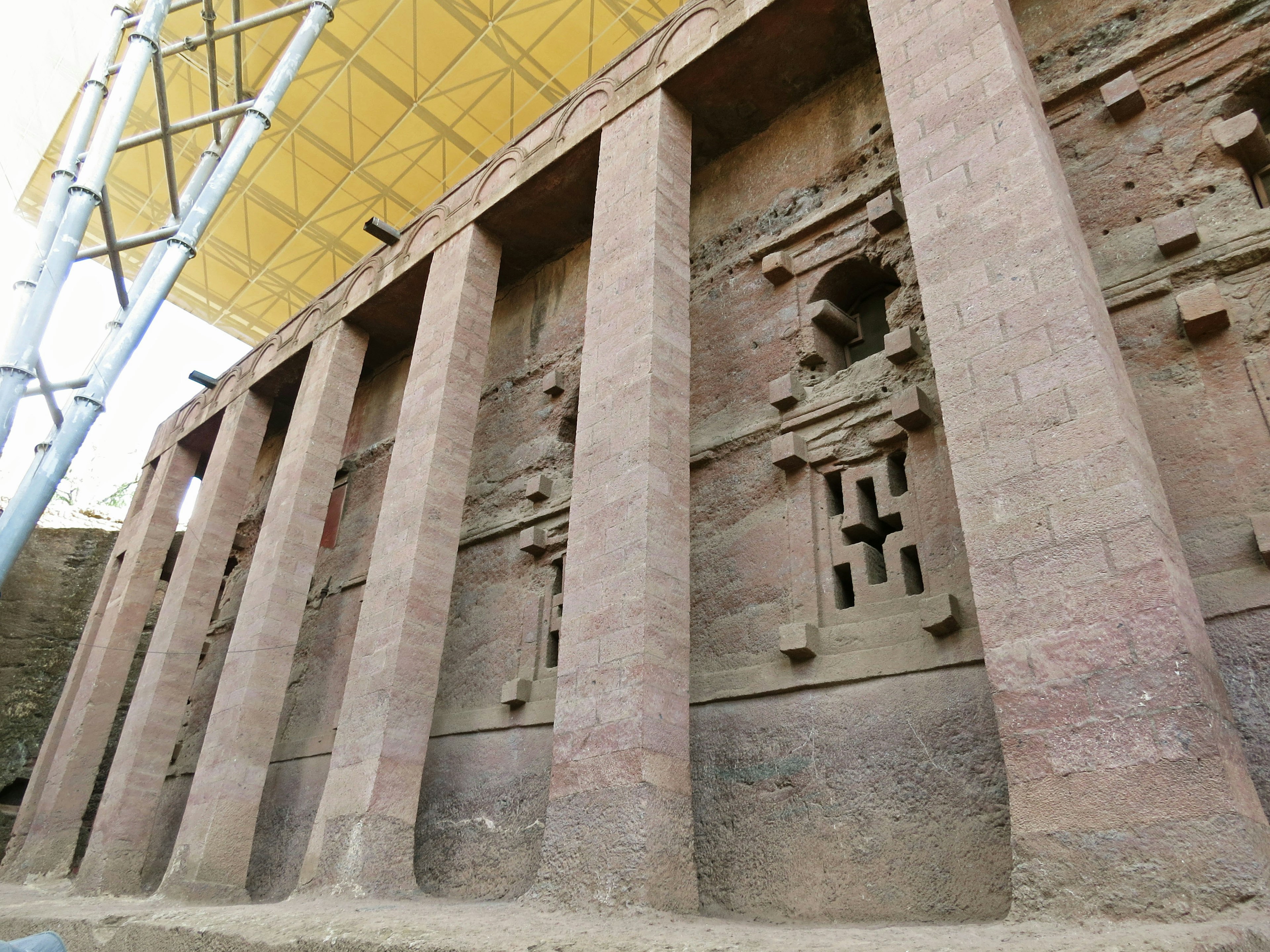 Extérieur des églises taillées dans le roc de Lalibela en Éthiopie montrant des colonnes en pierre et des sculptures