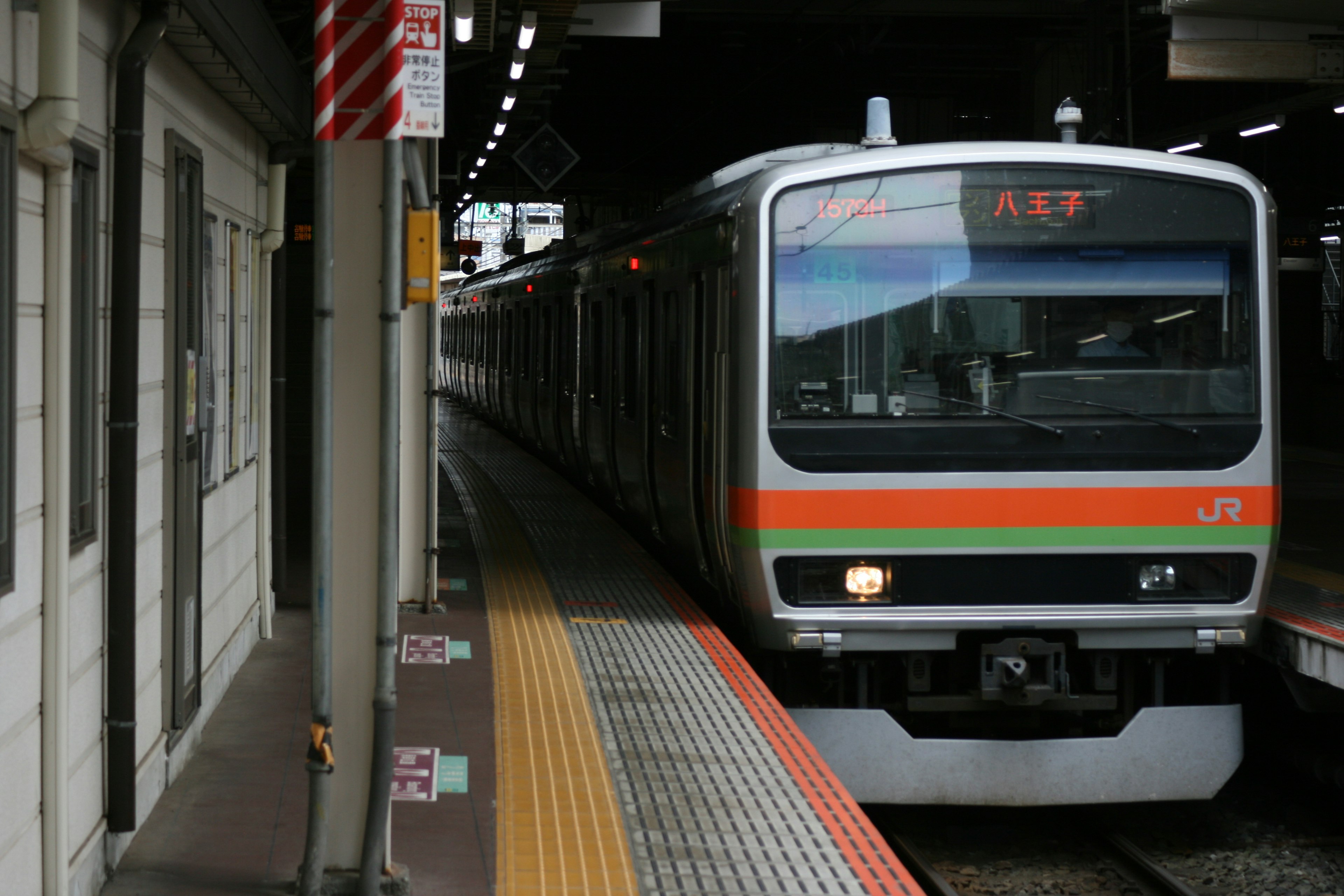 Train arriving at the station featuring green and orange stripes