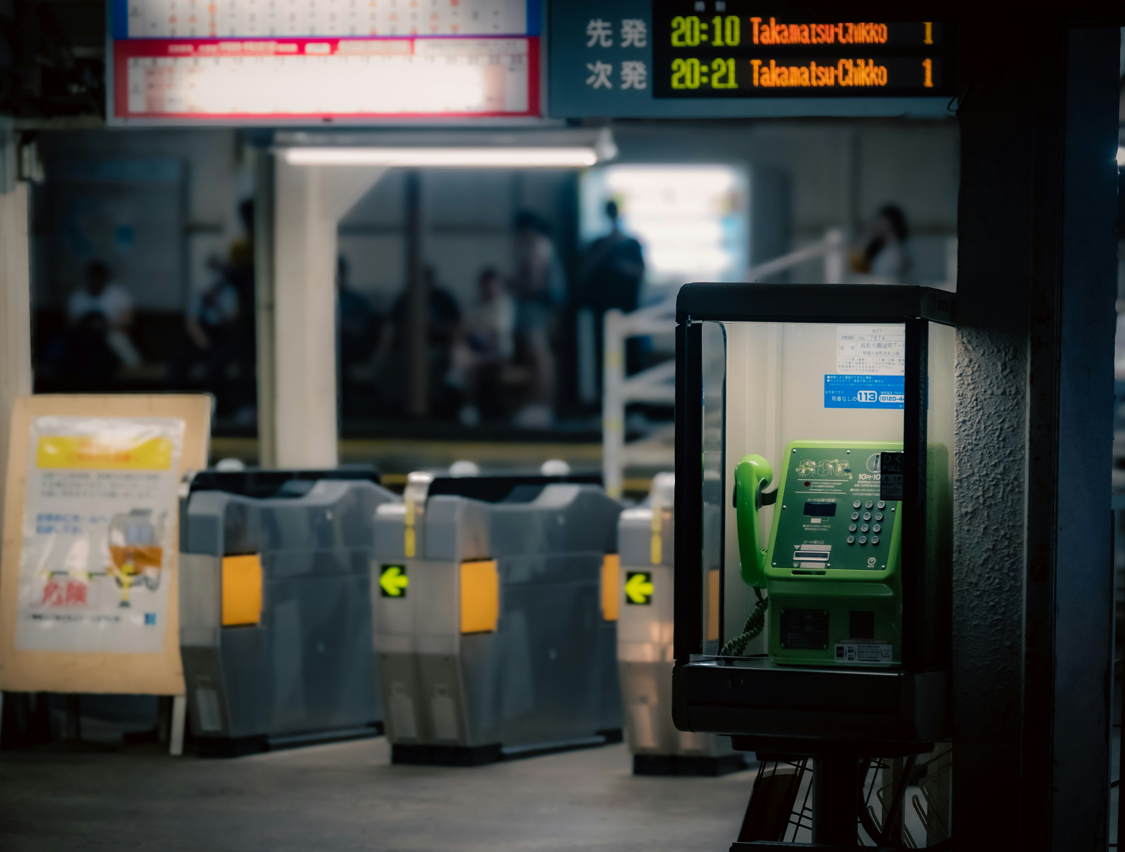 Une vue d'un téléphone public vert et de distributeurs de billets à l'intérieur d'une gare