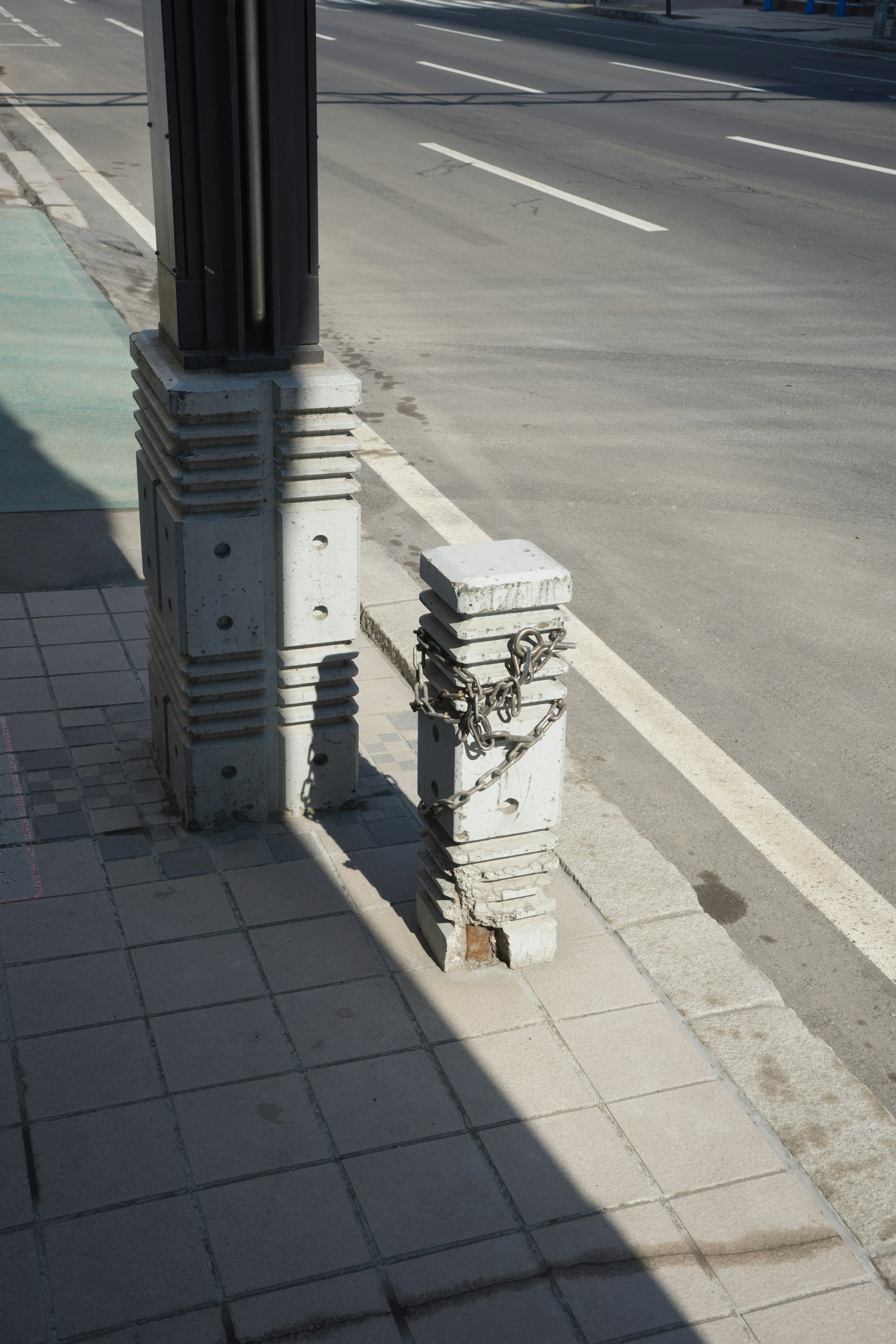 Polo de servicios de concreto en la acera con un pequeño poste de concreto al lado