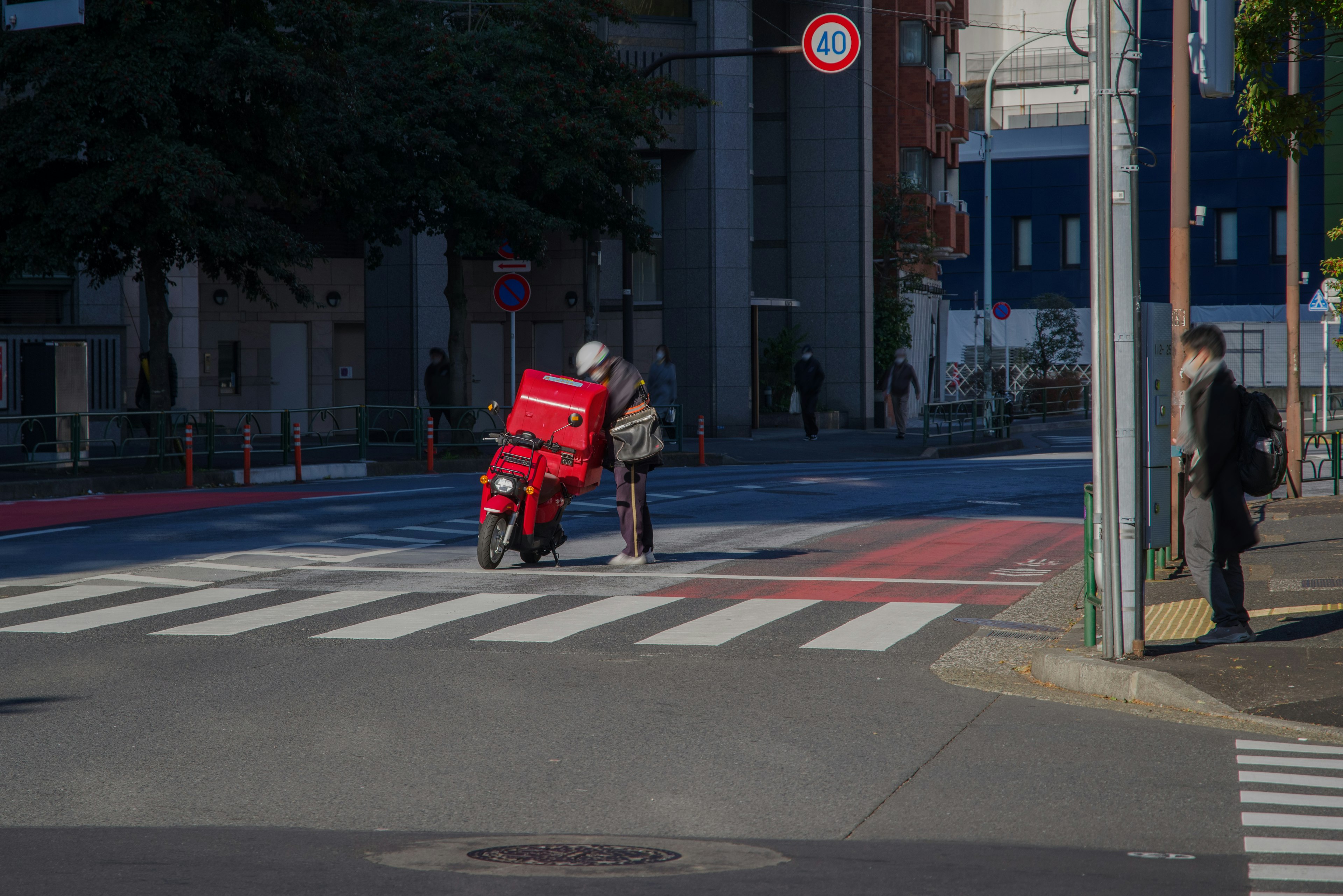 赤い配達バイクが交差点で停まっているシーン