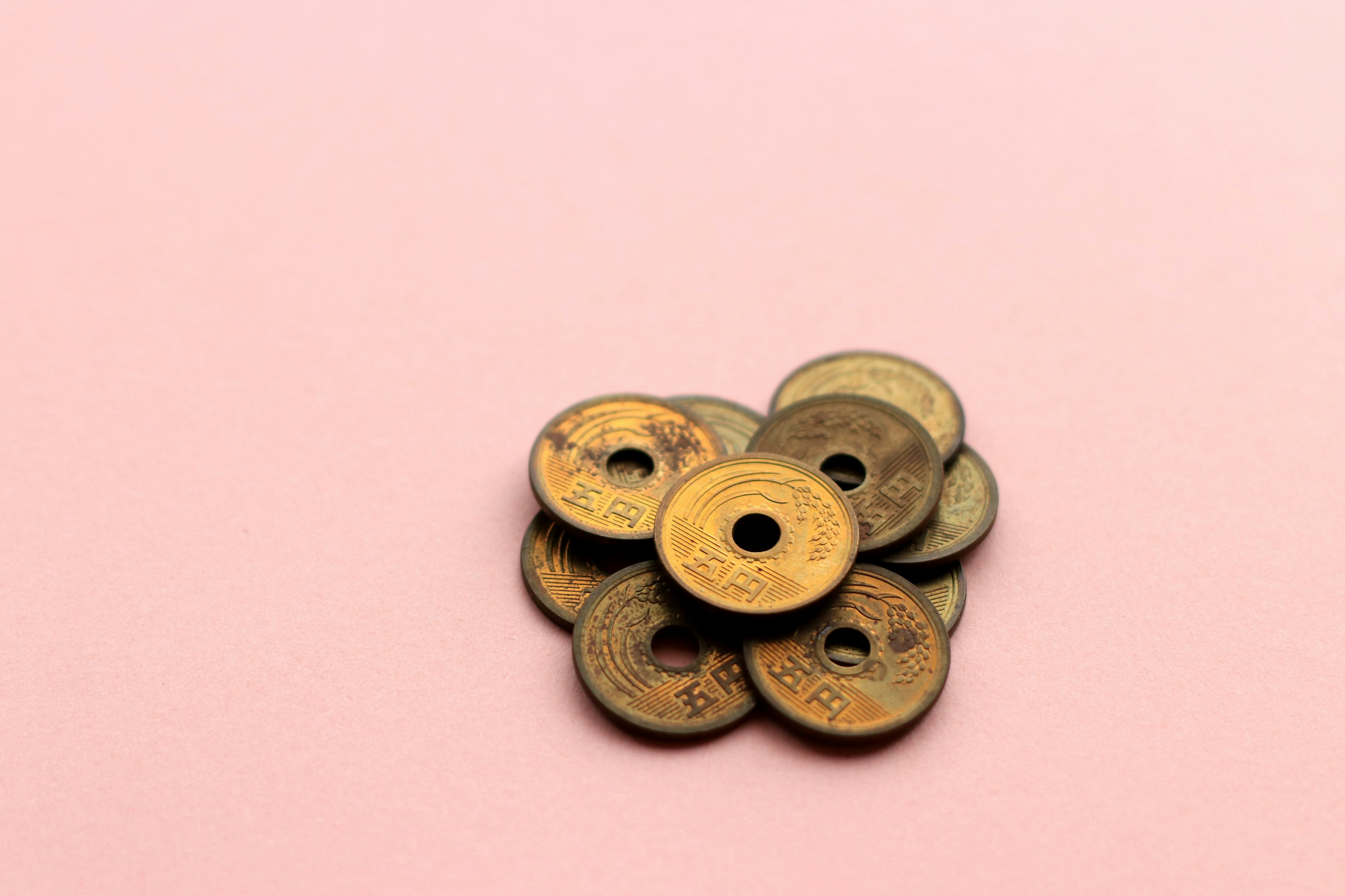 A pile of ancient coins on a pink background