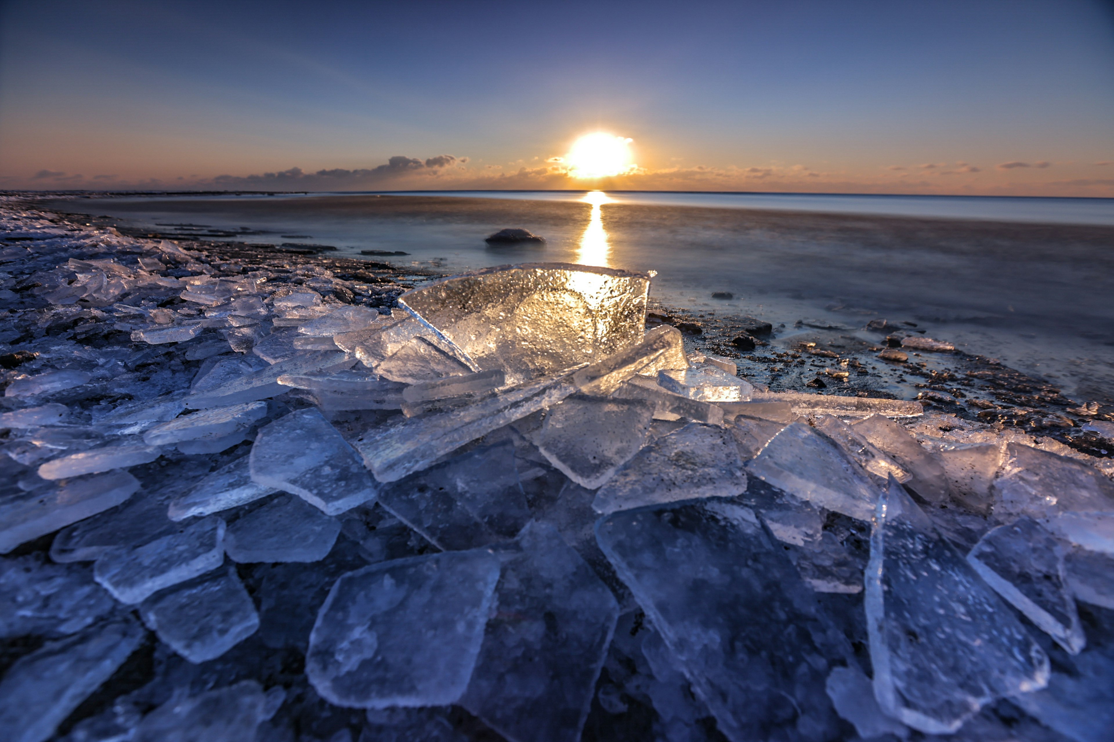 Landschaft mit Eisfragmenten und einem Sonnenuntergang über dem Meer