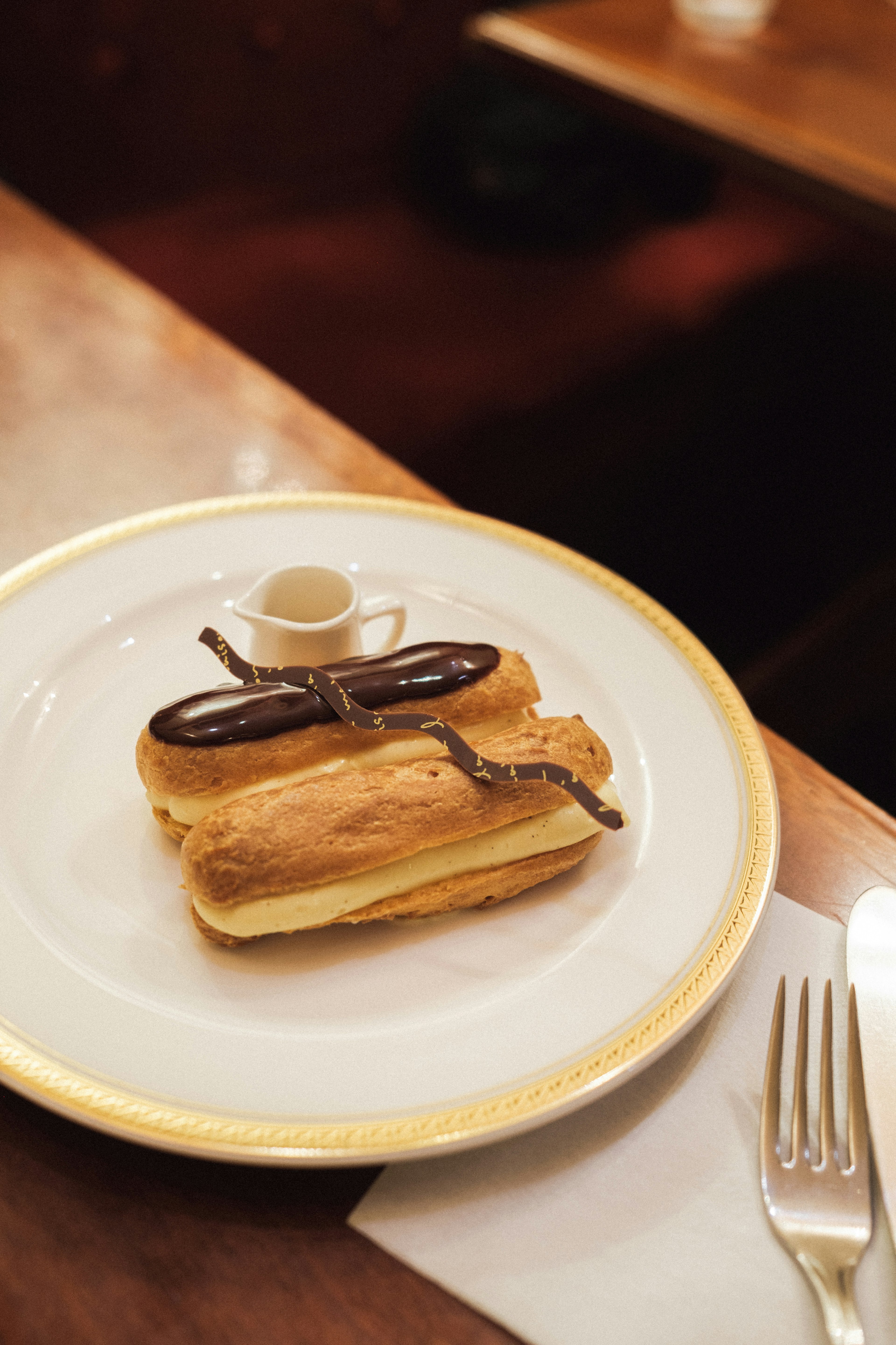 Eclair auf einem Teller mit einer kleinen Kaffeetasse