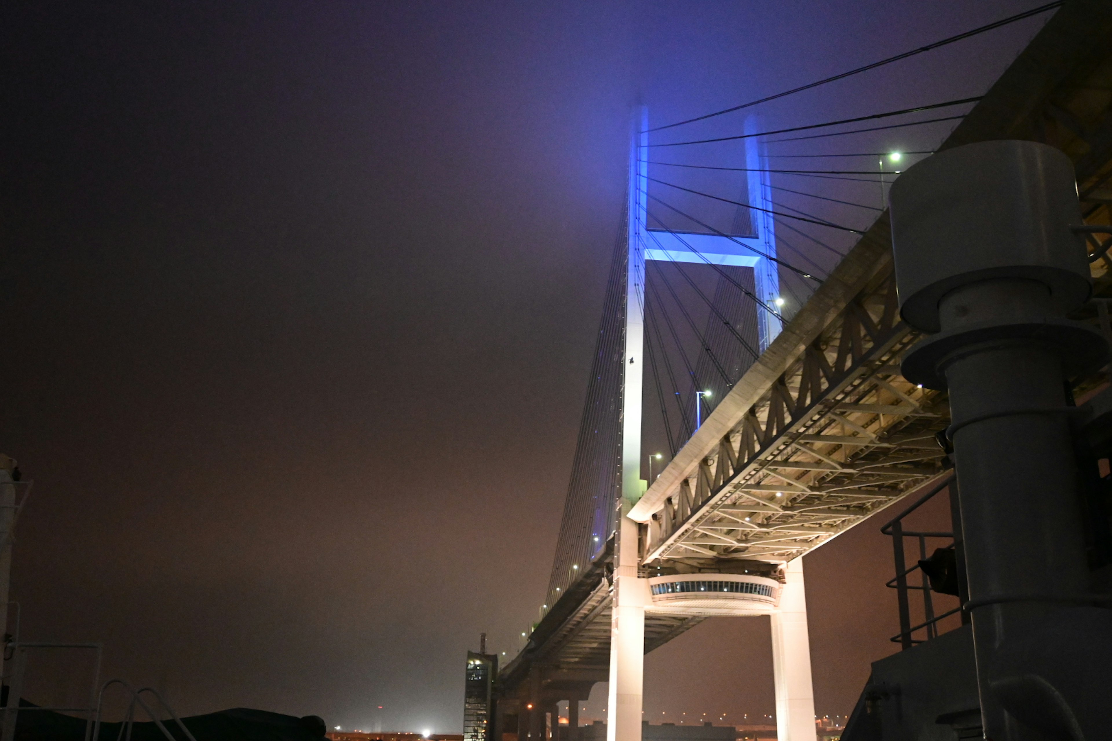 Vue nocturne du pont de Yokohama illuminé par des lumières bleues dans le brouillard