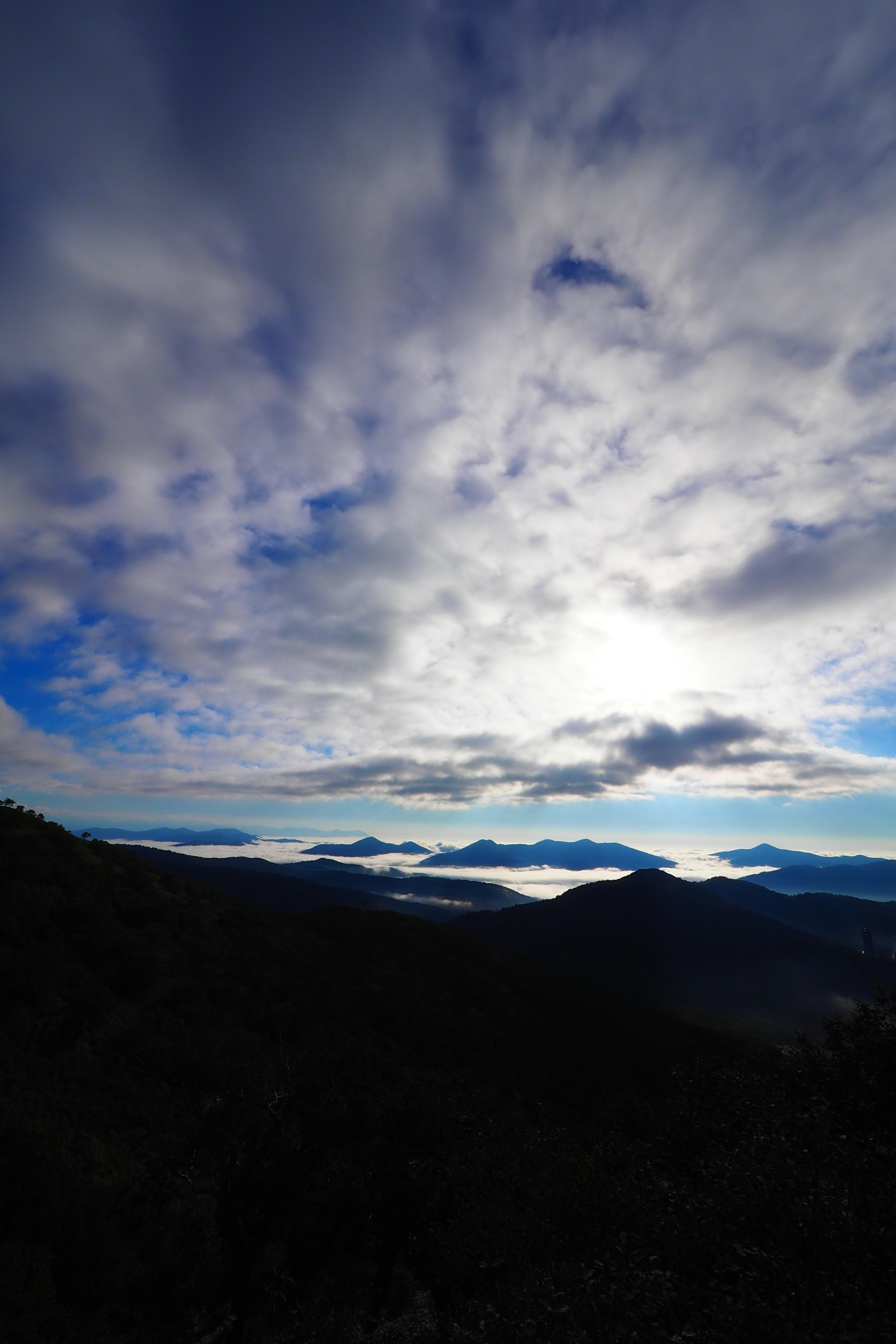 青い空に雲が広がり、遠くの山々が見える風景