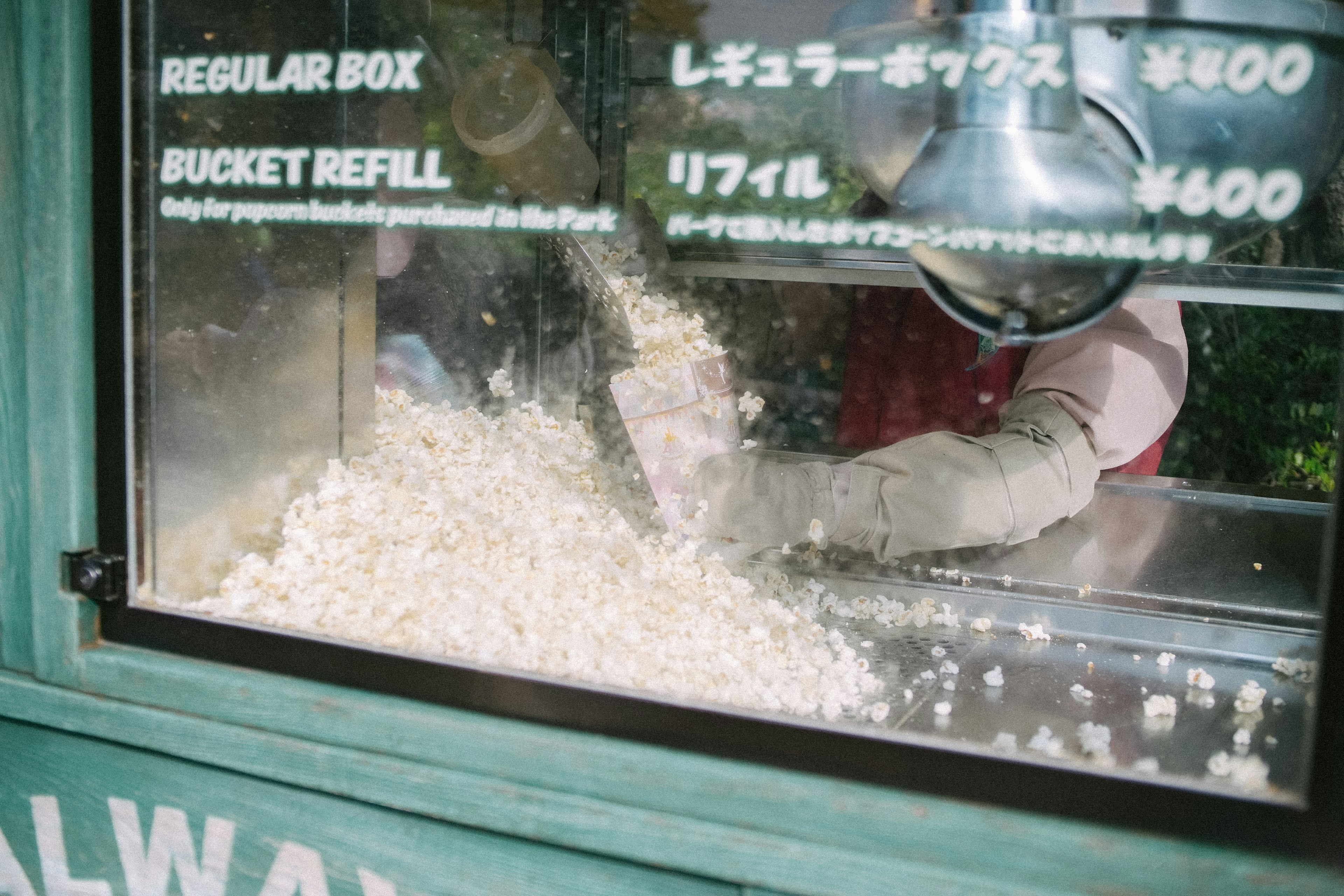 Popcorn being served from a vendor's window with pricing details visible