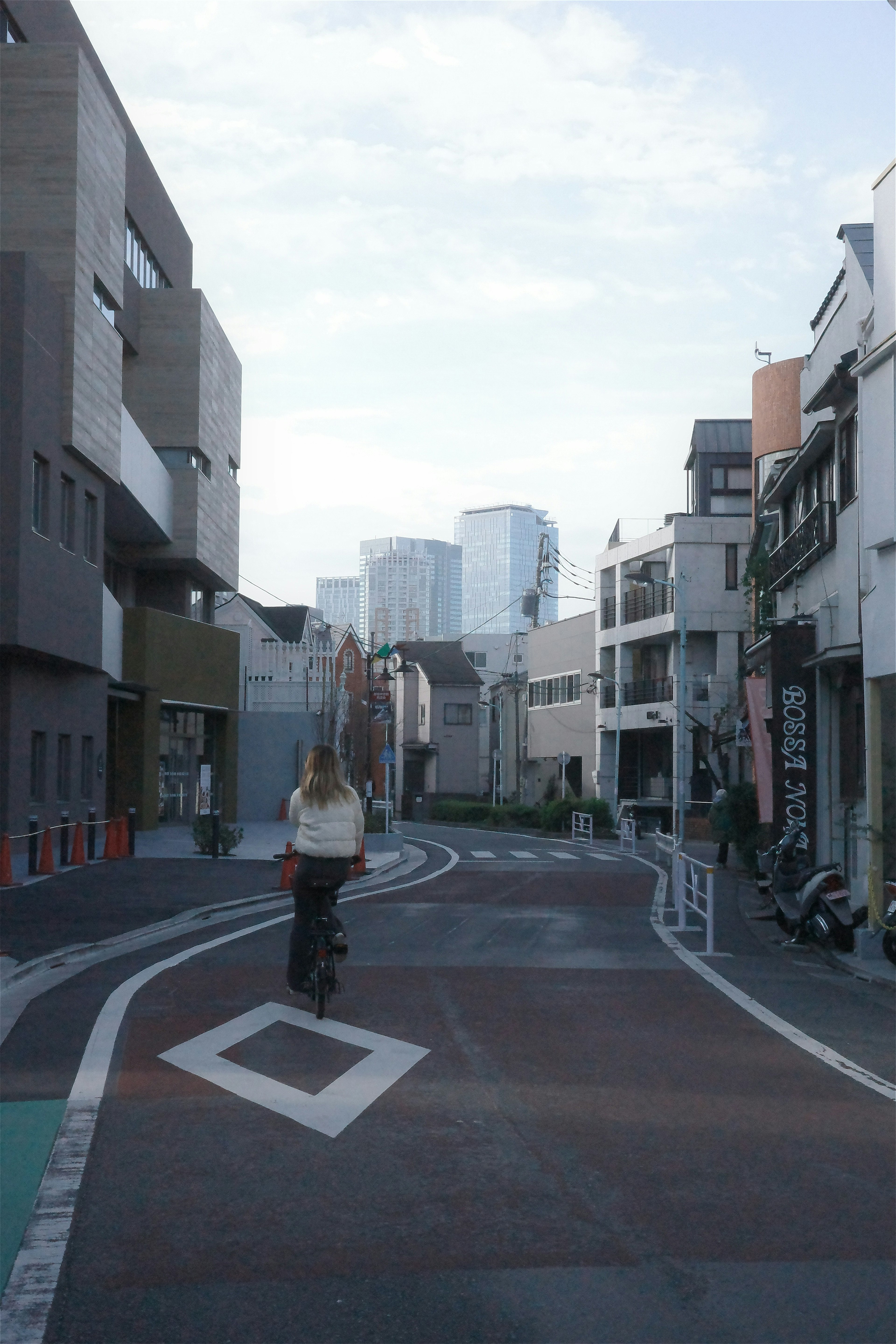 Un ciclista en una calle con edificios modernos al fondo