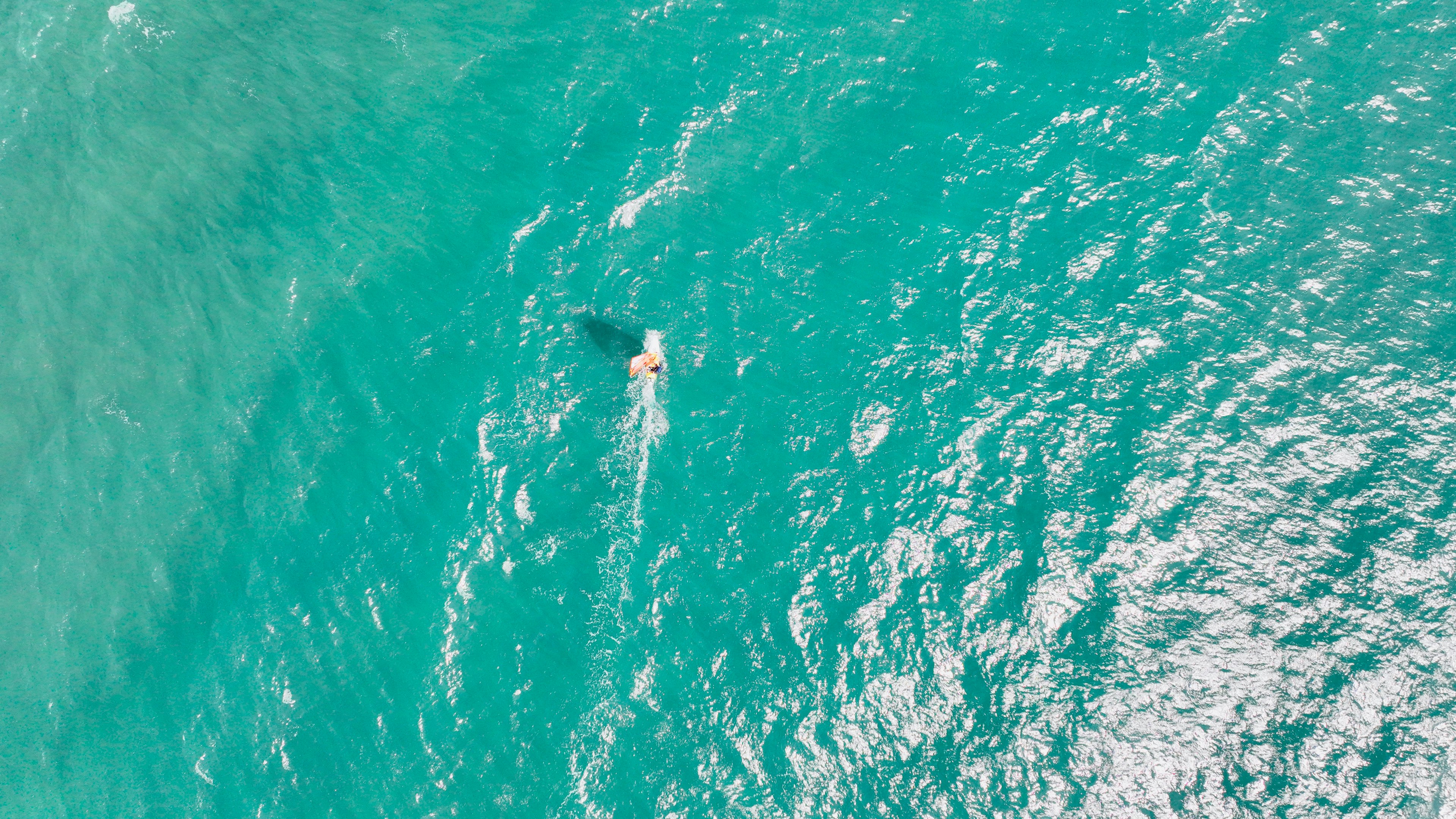 青い海の中で泳ぐ人の上空からの写真