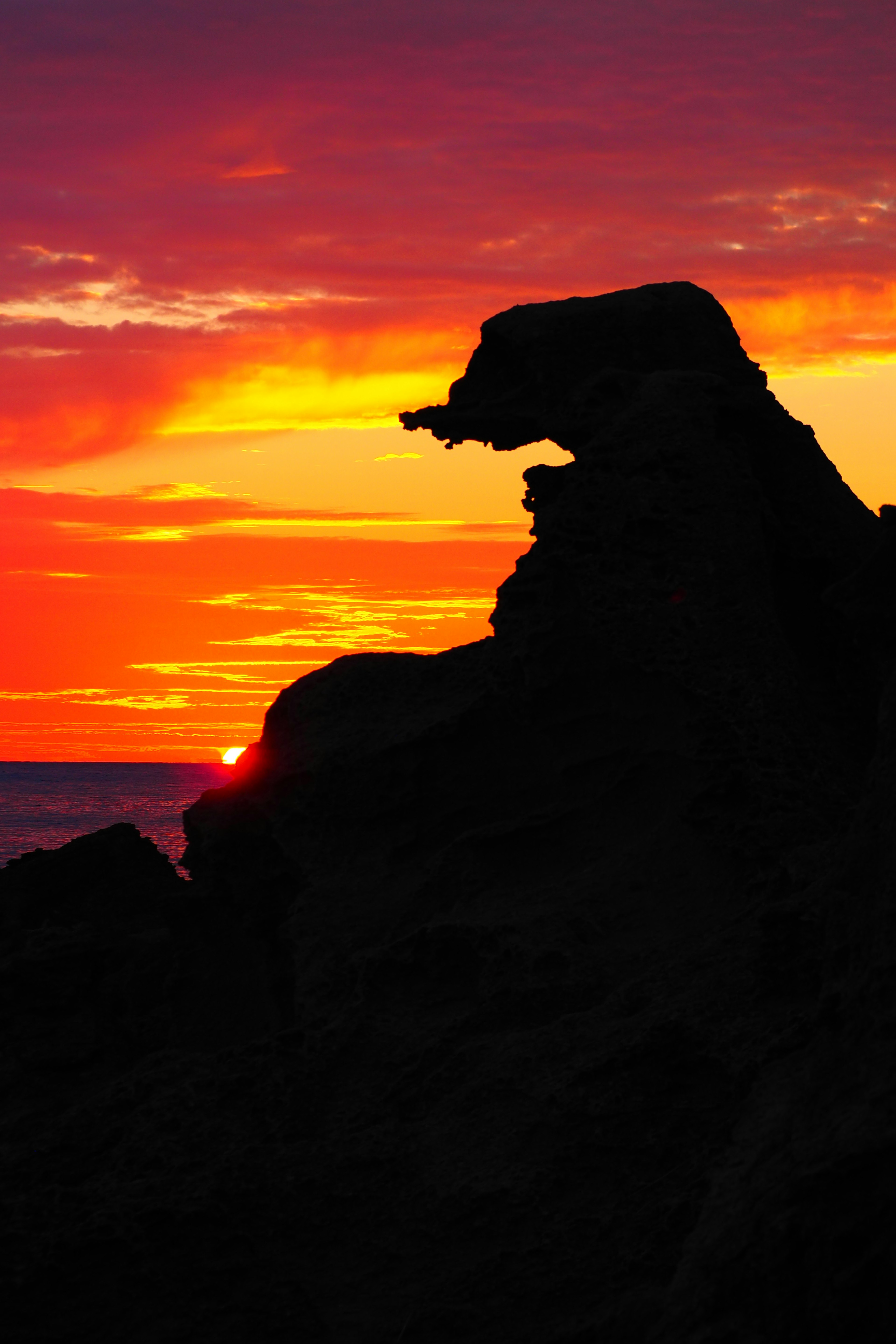 Silhouette of a rock formation against a vibrant sunset