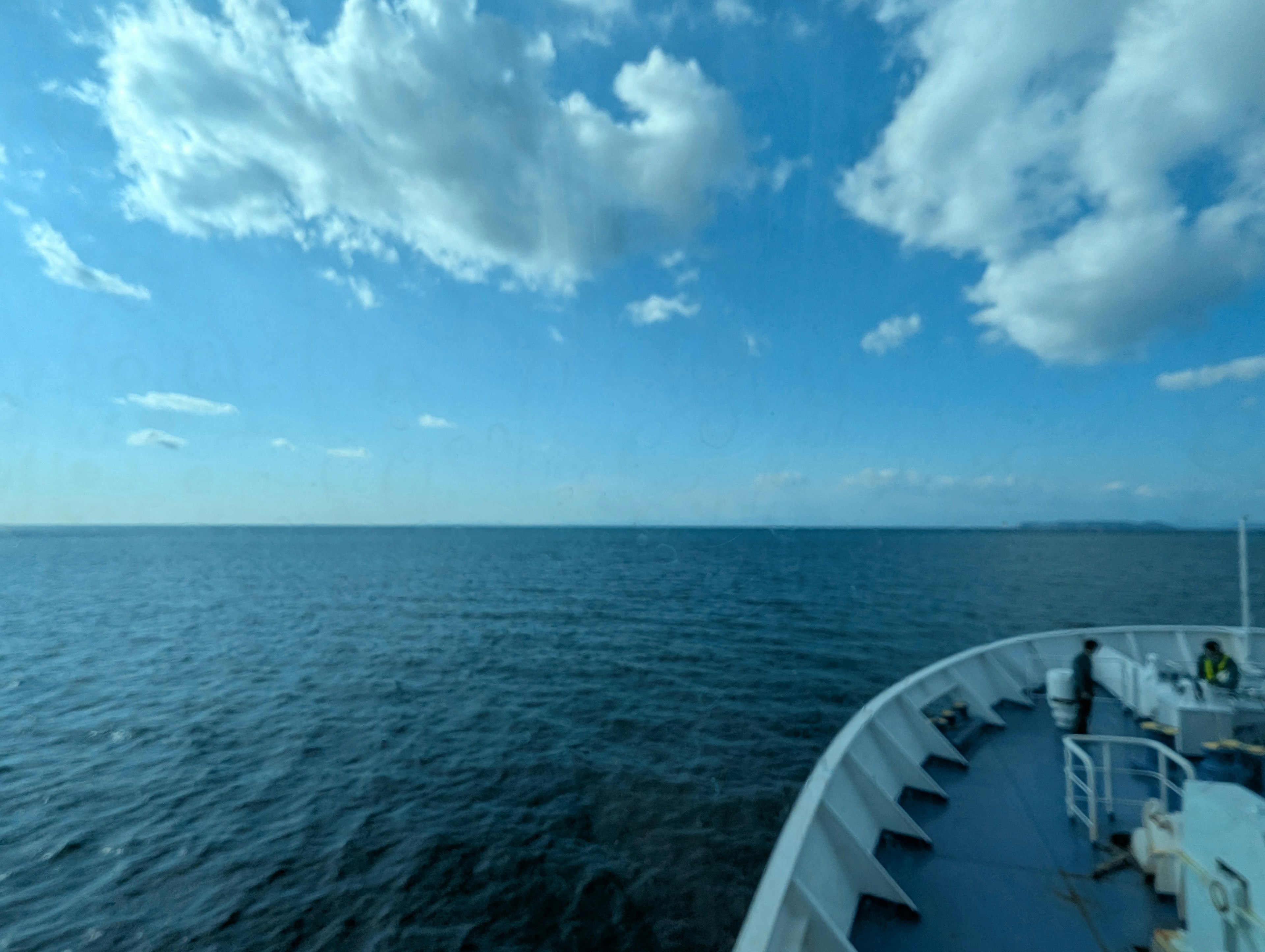 Pemandangan laut biru dan langit cerah dengan sisi kapal terlihat