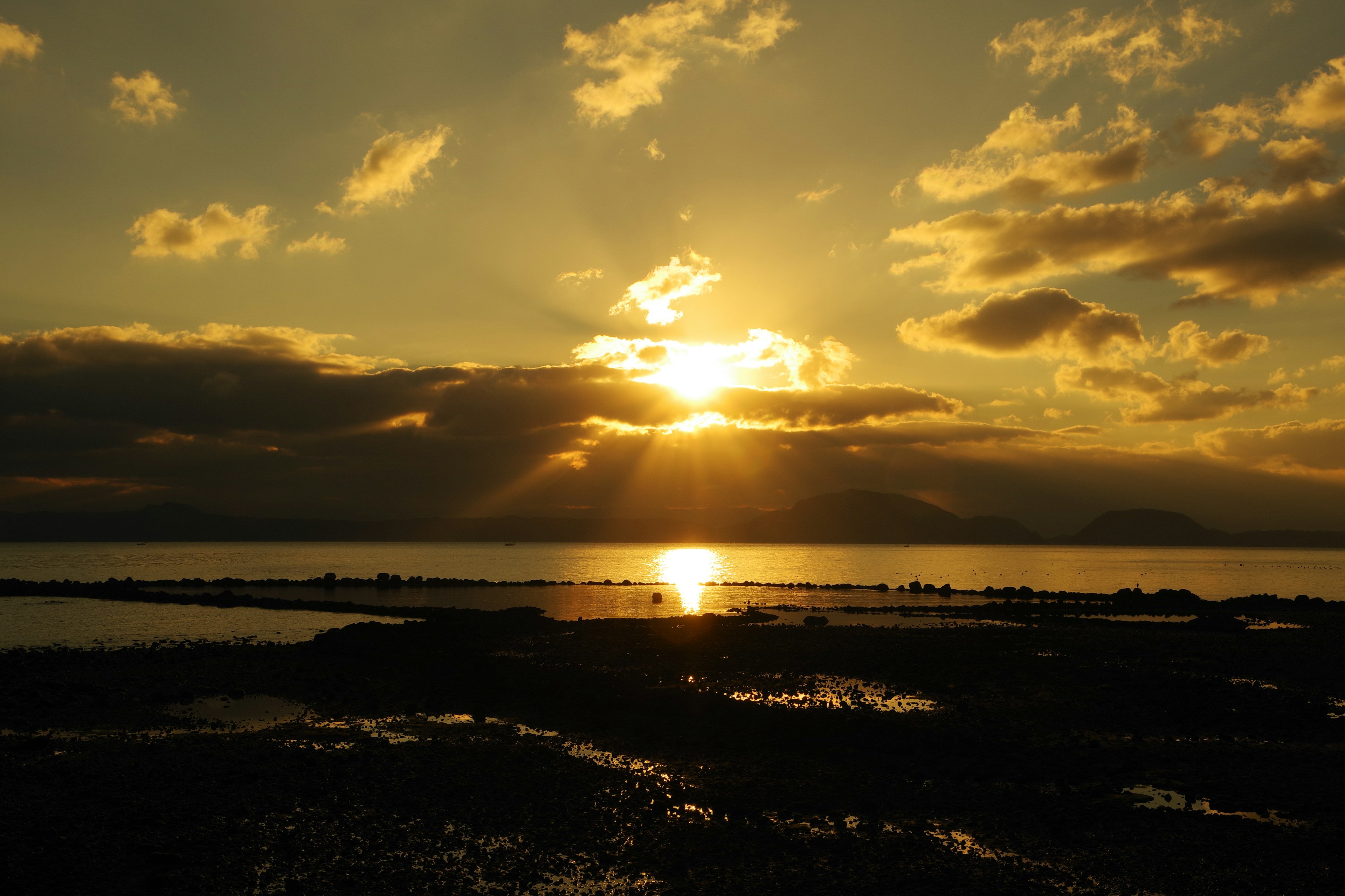 Sunset over the ocean with silhouettes of clouds