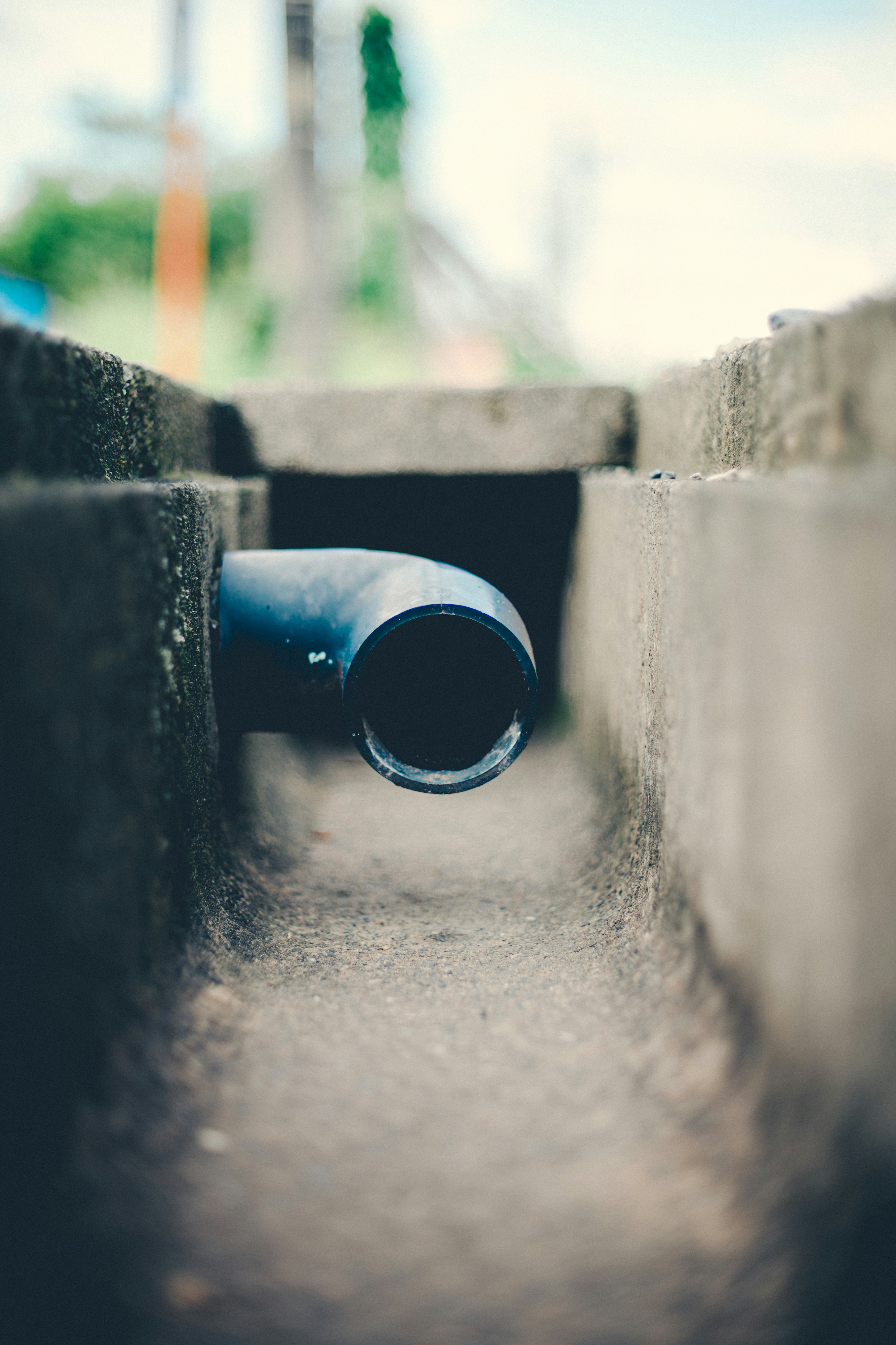 Un tuyau bleu sort d'un drain en béton