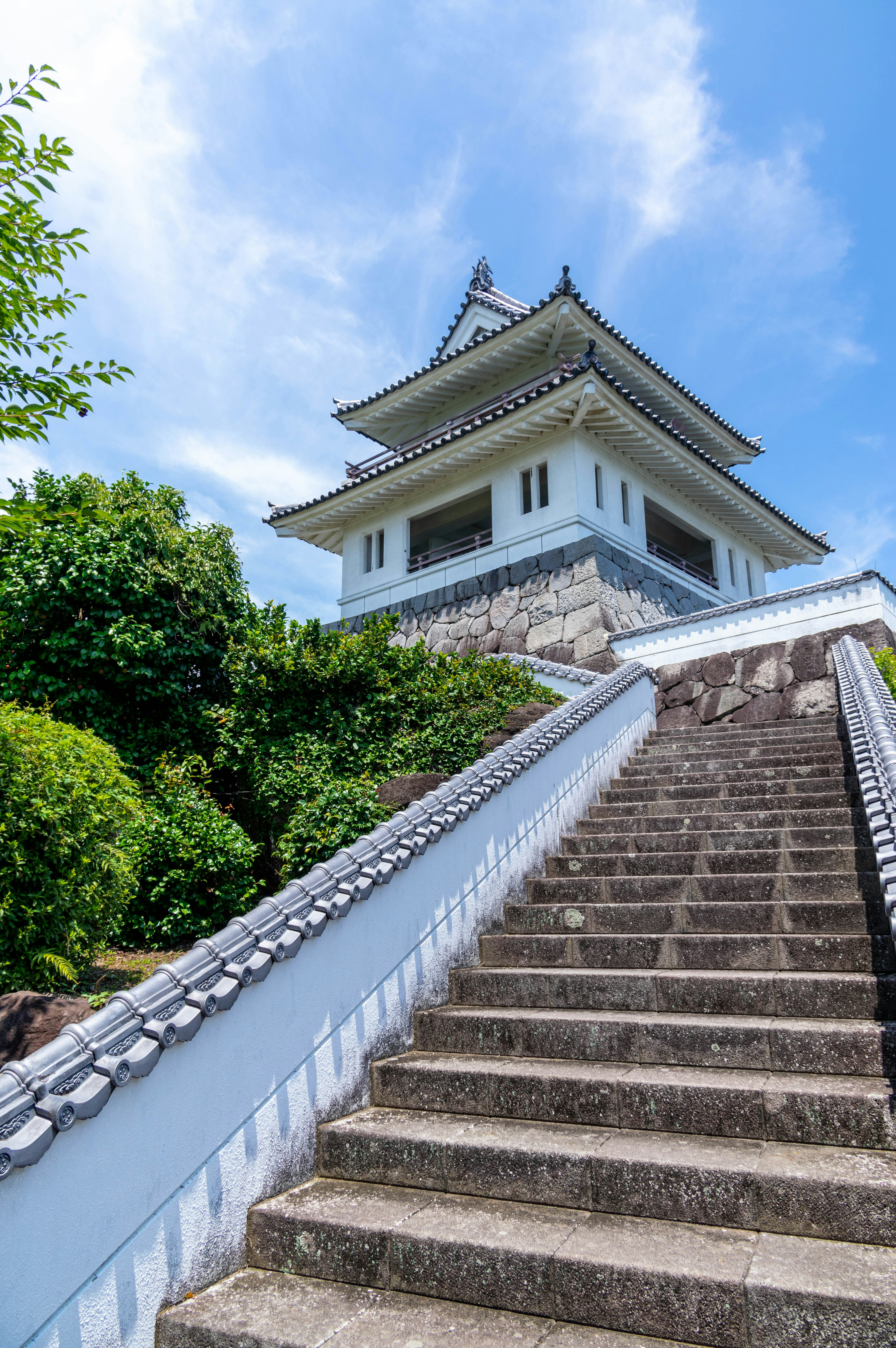 Beau château japonais visible depuis des escaliers en pierre blanche