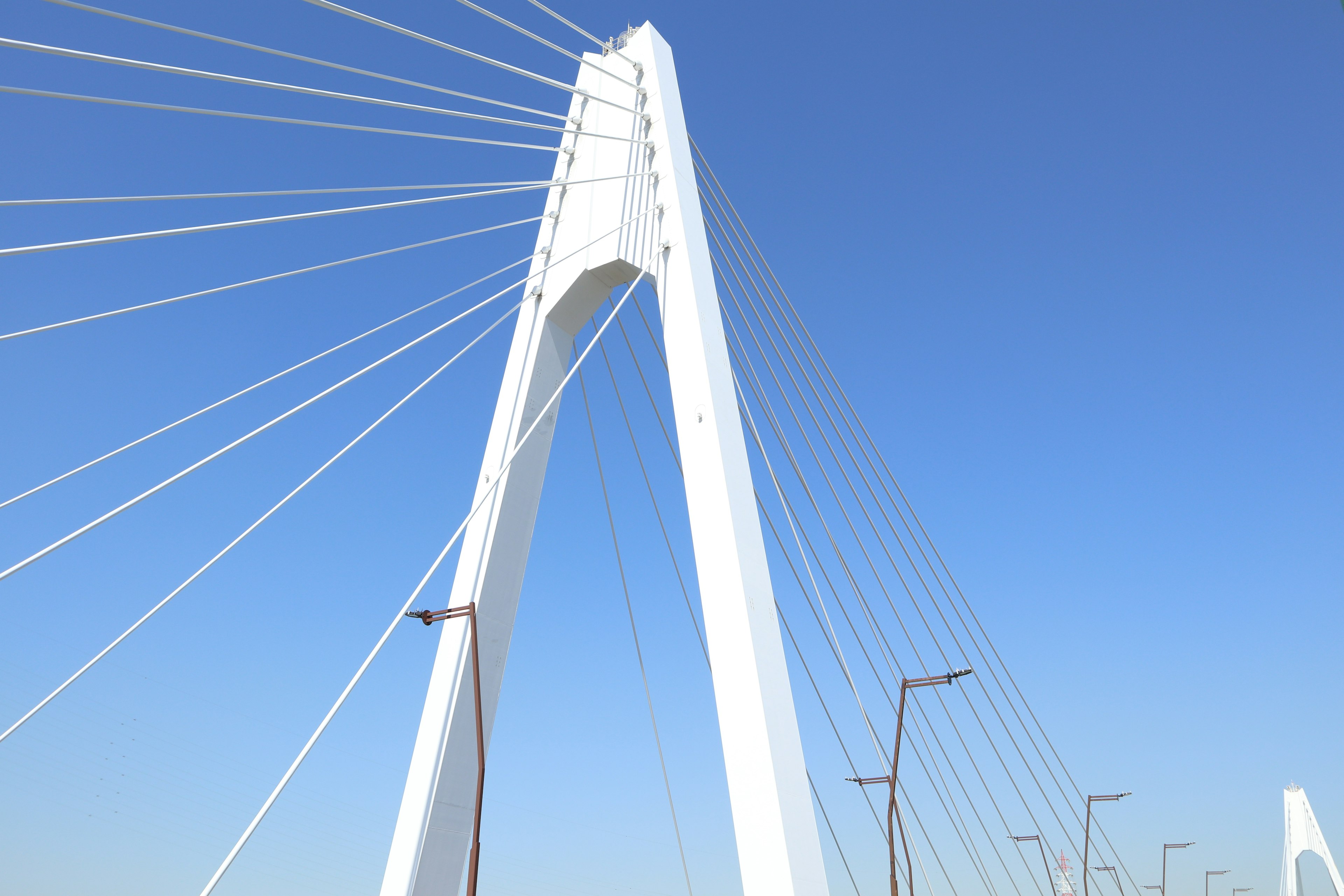 Une tour de pont à haubans blanche sous un ciel bleu clair