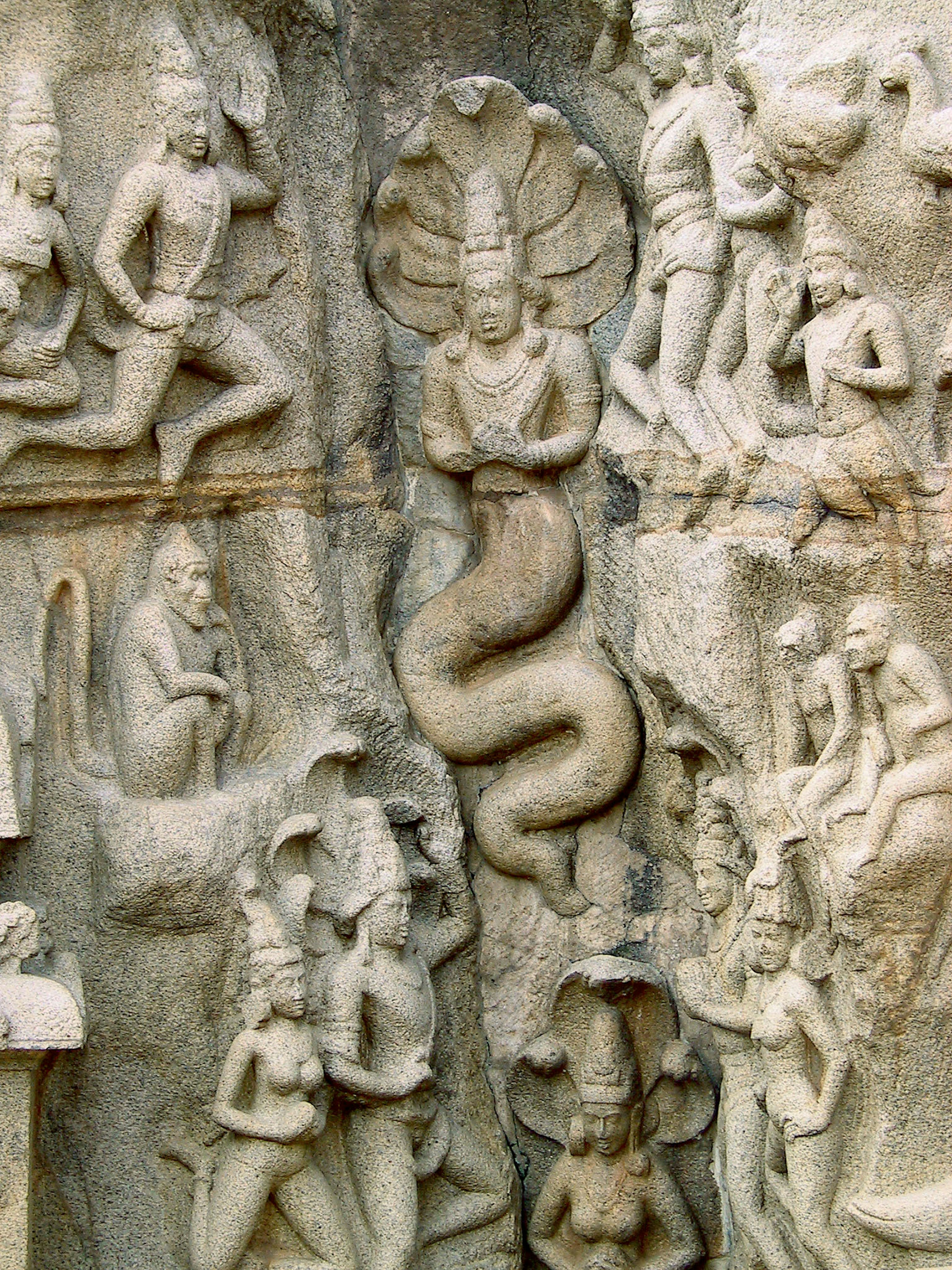 Sculptures anciennes sur un mur en pierre représentant des divinités et un dieu serpent