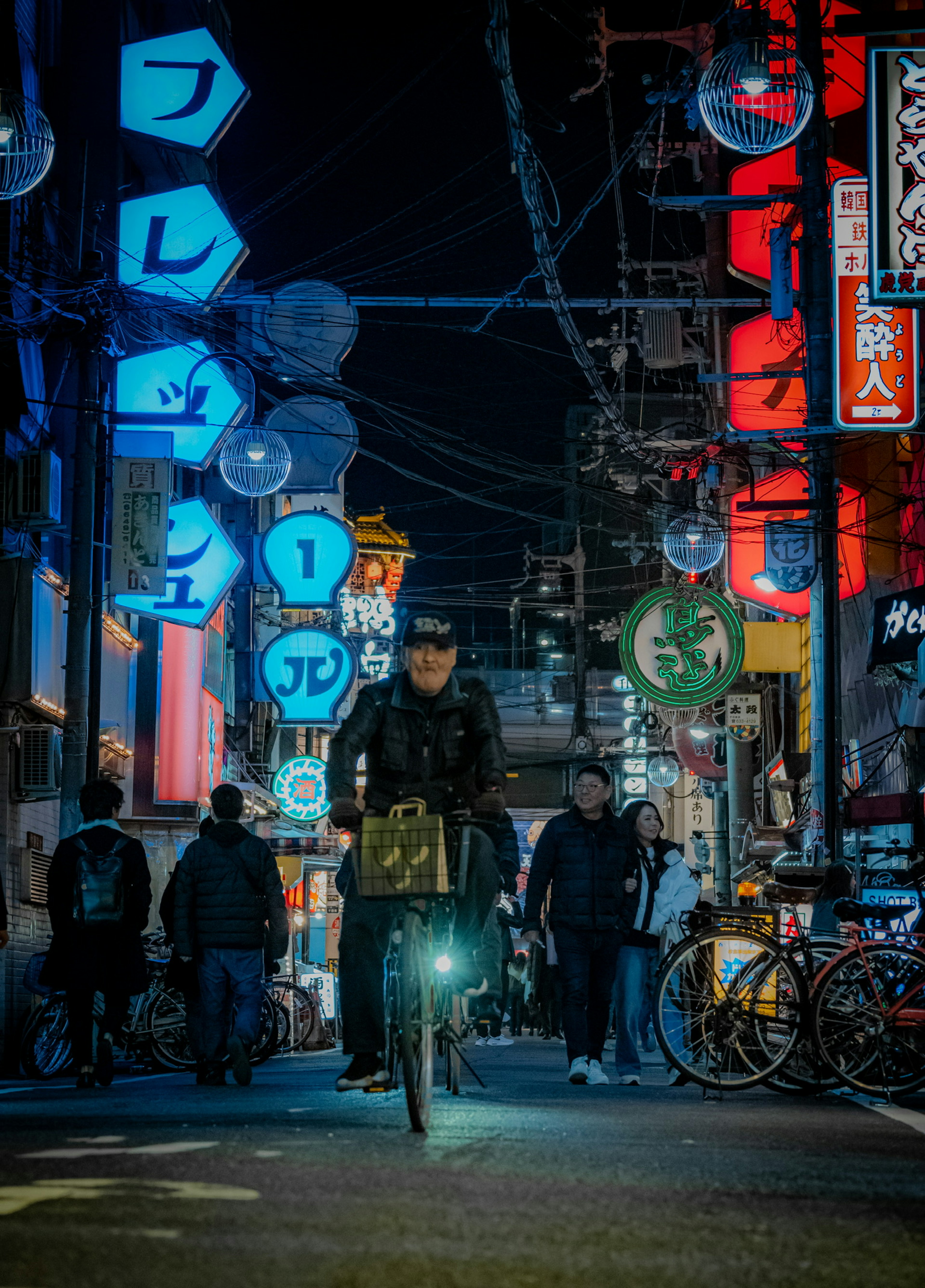 Person auf einem Fahrrad in einer Stadtstraße mit Neonlichtern bei Nacht