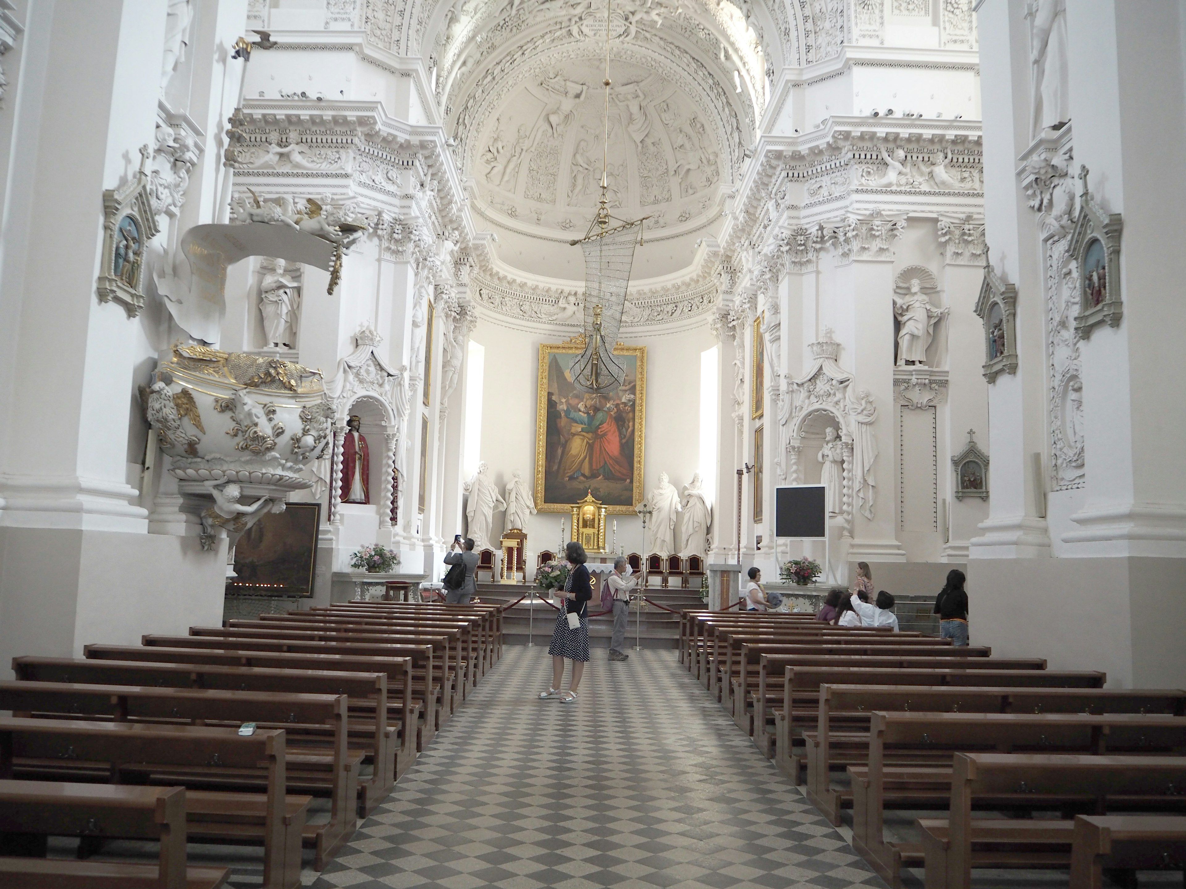 Innenansicht einer Kirche mit weißen Wänden und komplizierten Verzierungen Holzbänke und eine hohe Decke