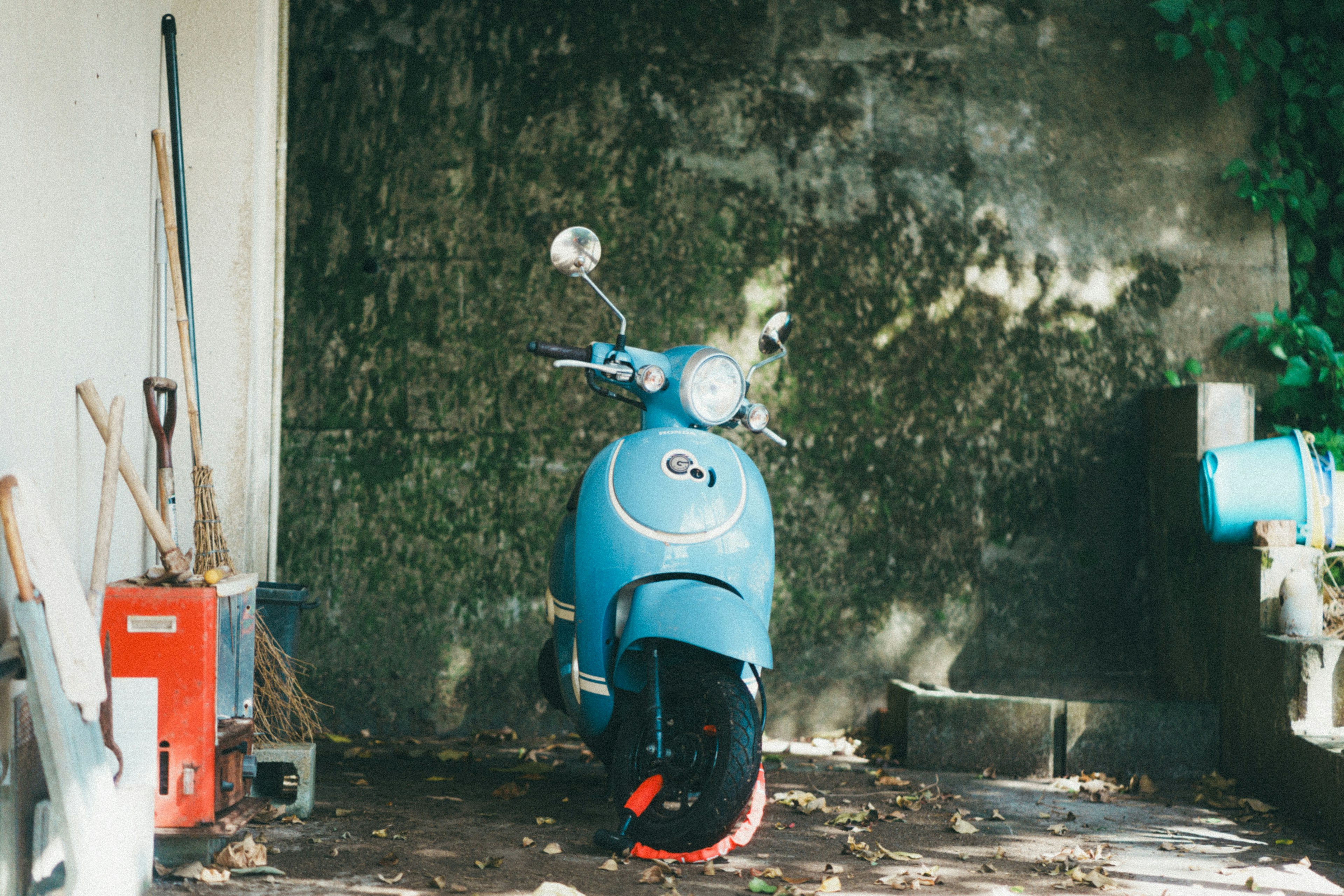 A blue scooter parked in front of a textured wall