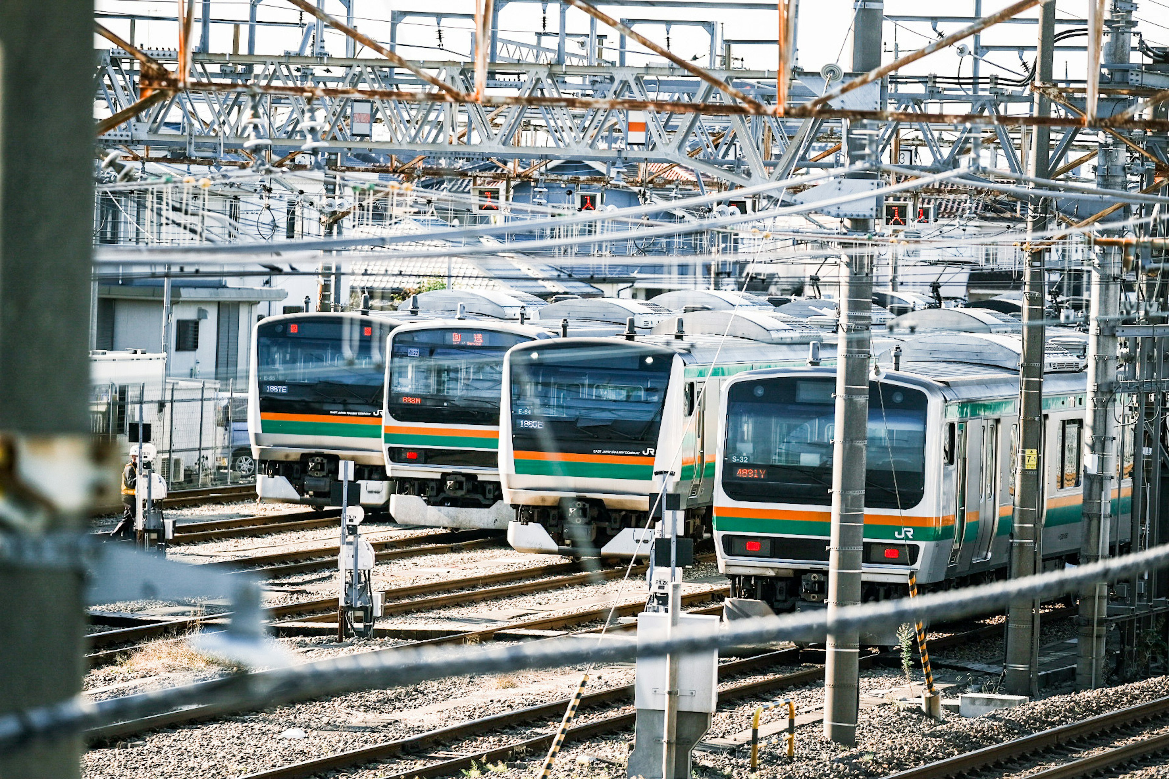 Múltiples trenes alineados en las vías con cables aéreos visibles