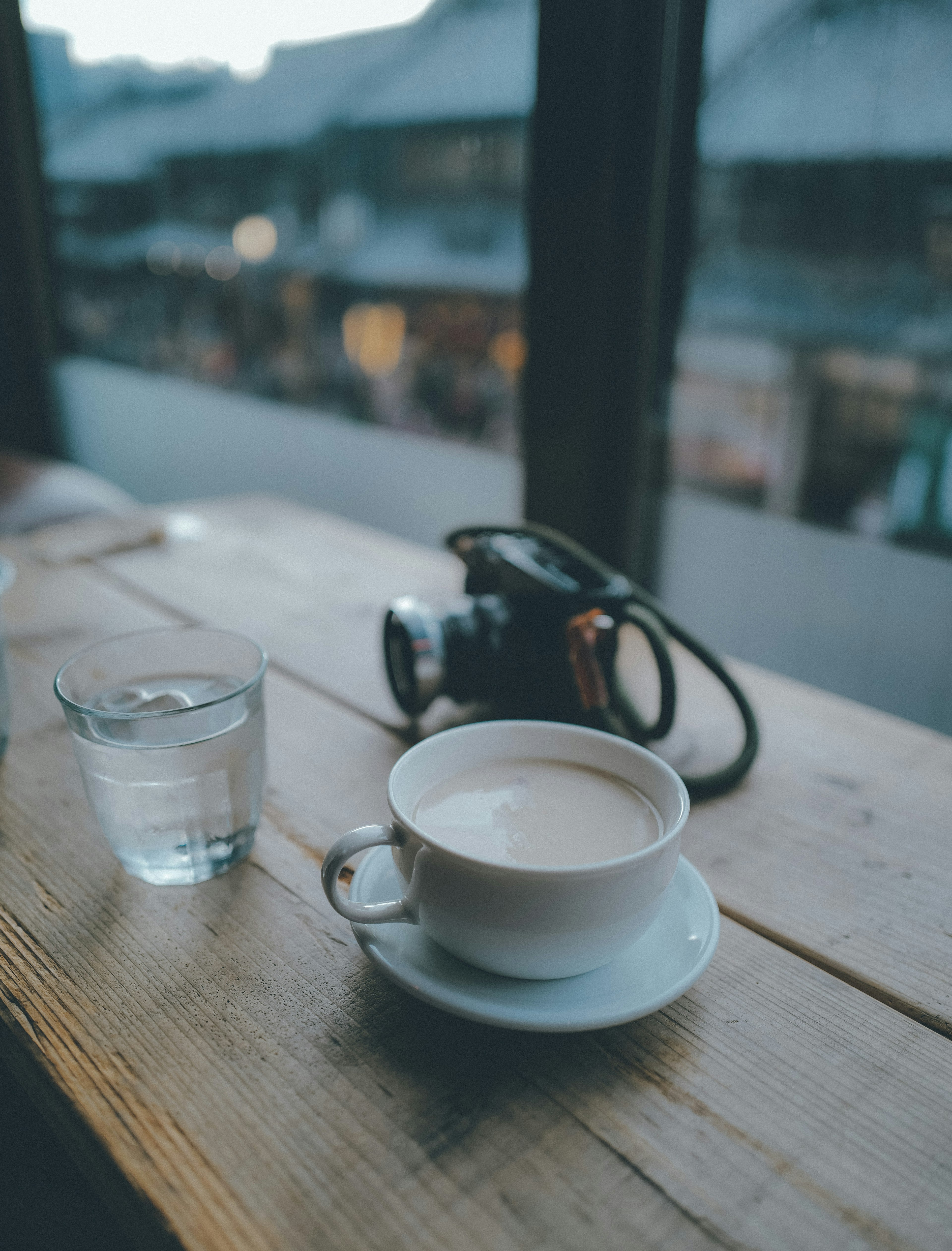 A cup of coffee and a glass of water on a wooden table in a cozy café