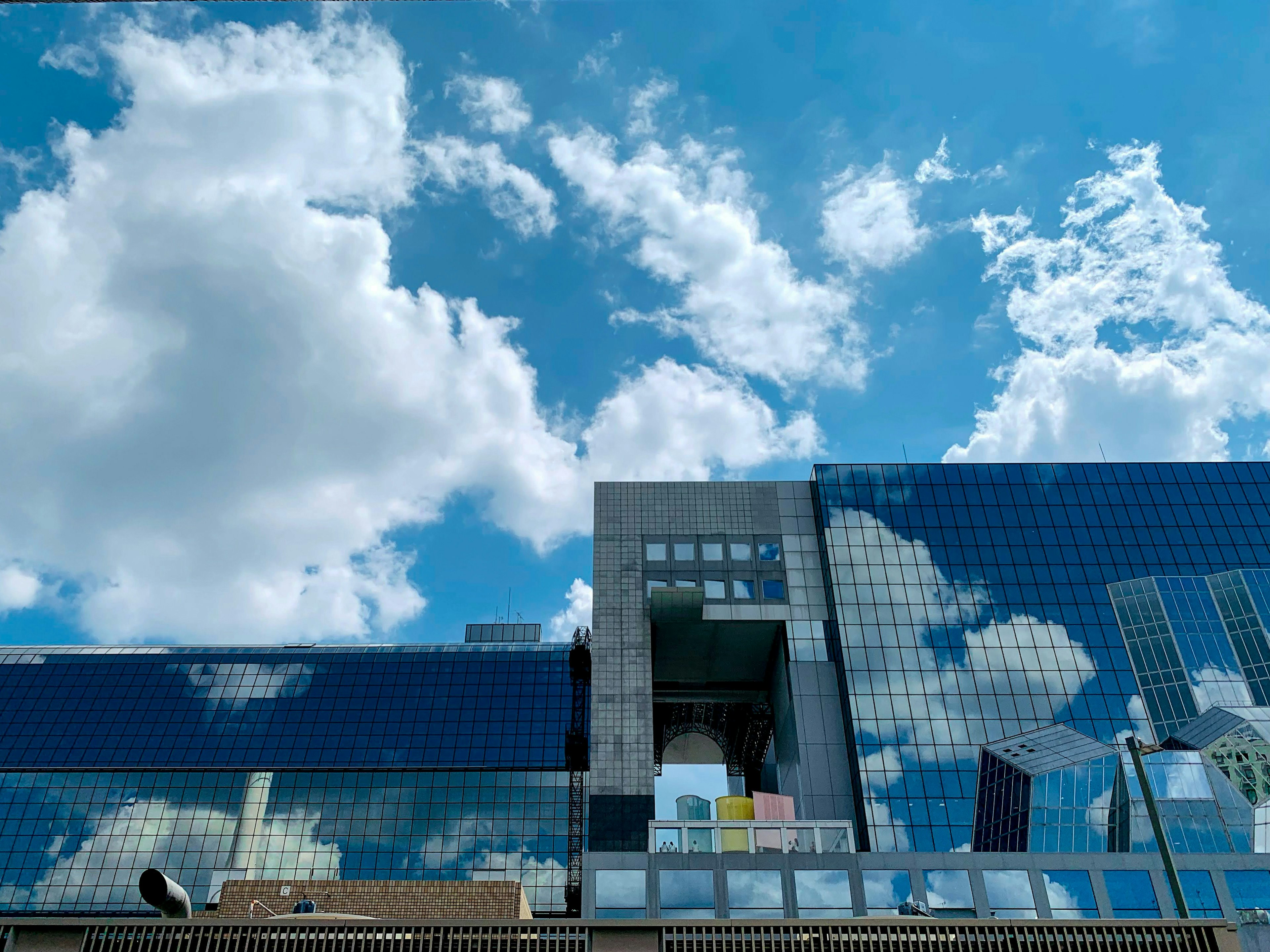 Modern building reflecting blue sky and white clouds