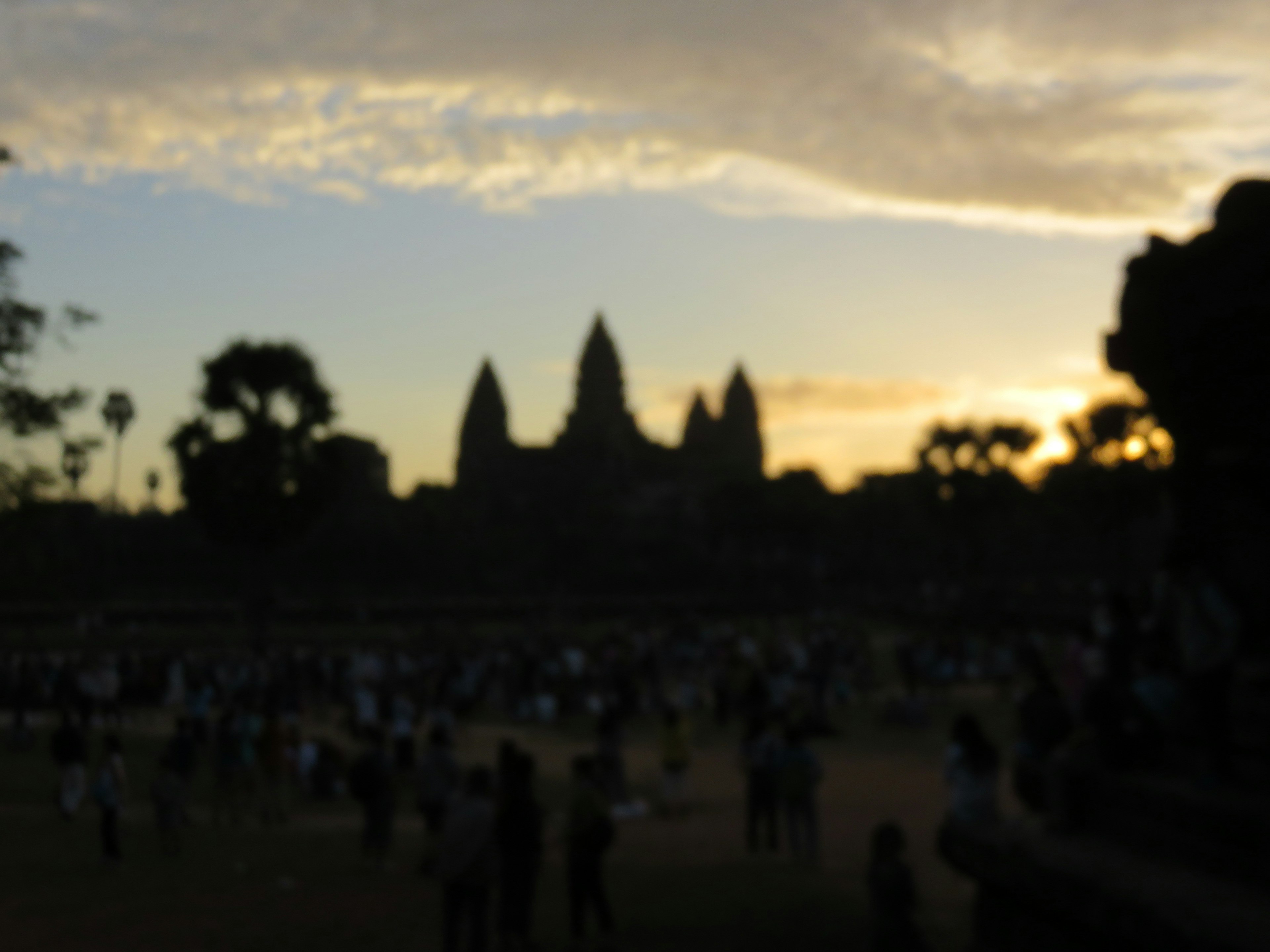 Siluet Angkor Wat saat matahari terbenam dengan wisatawan