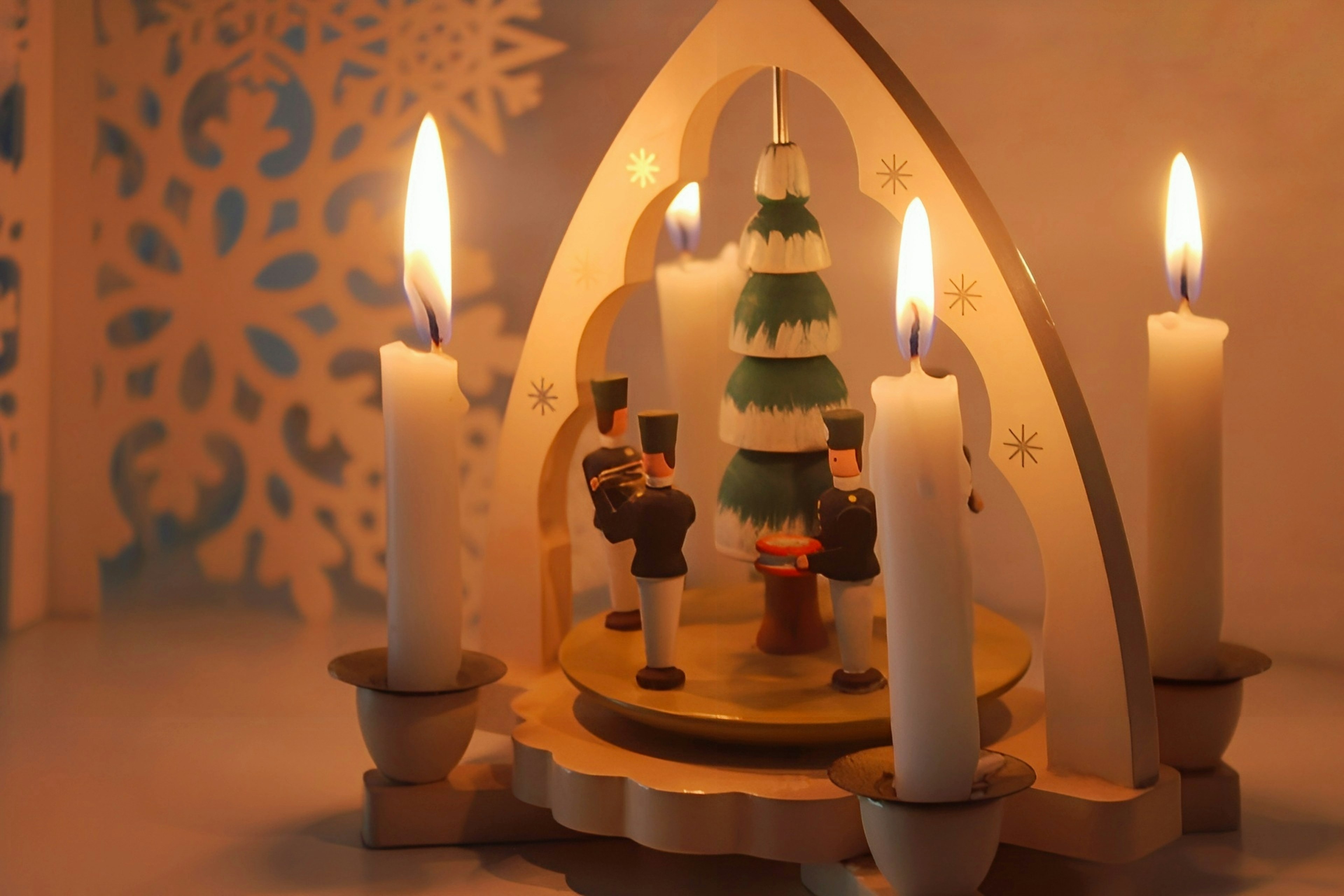 Decorazione natalizia con candele e figure di legno intorno a un albero di Natale verde