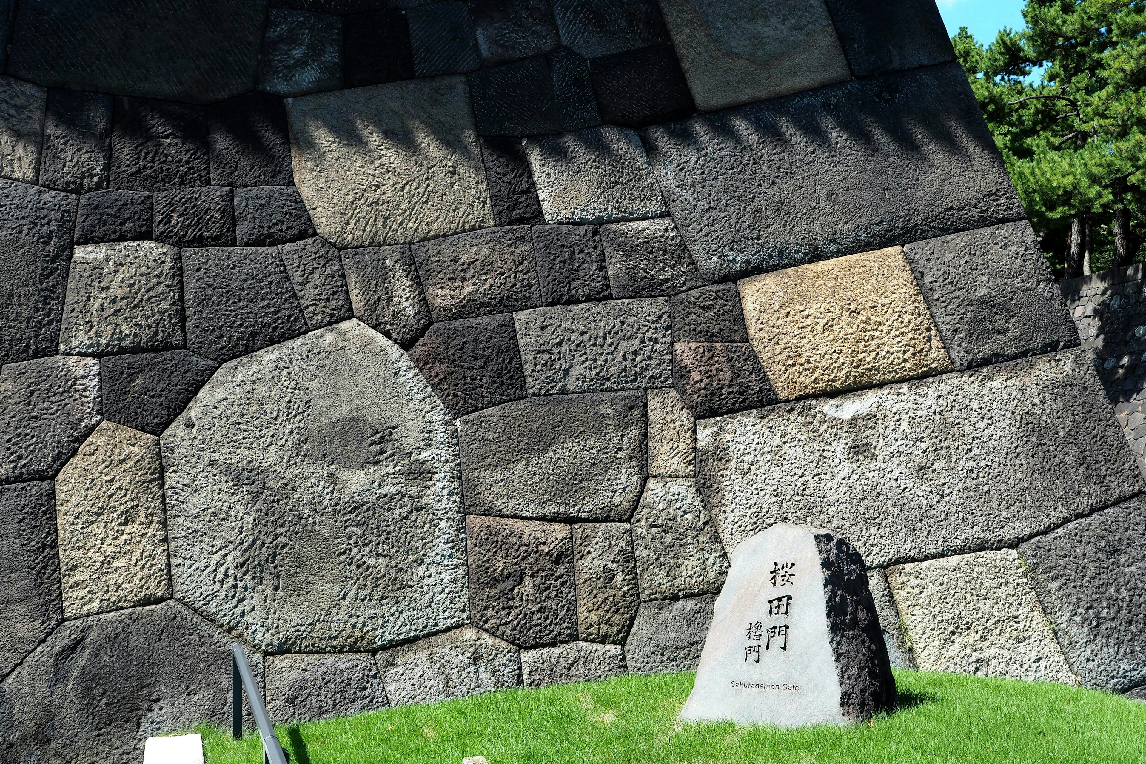 Ancient stone wall structure with distinct patterns and grass landscape