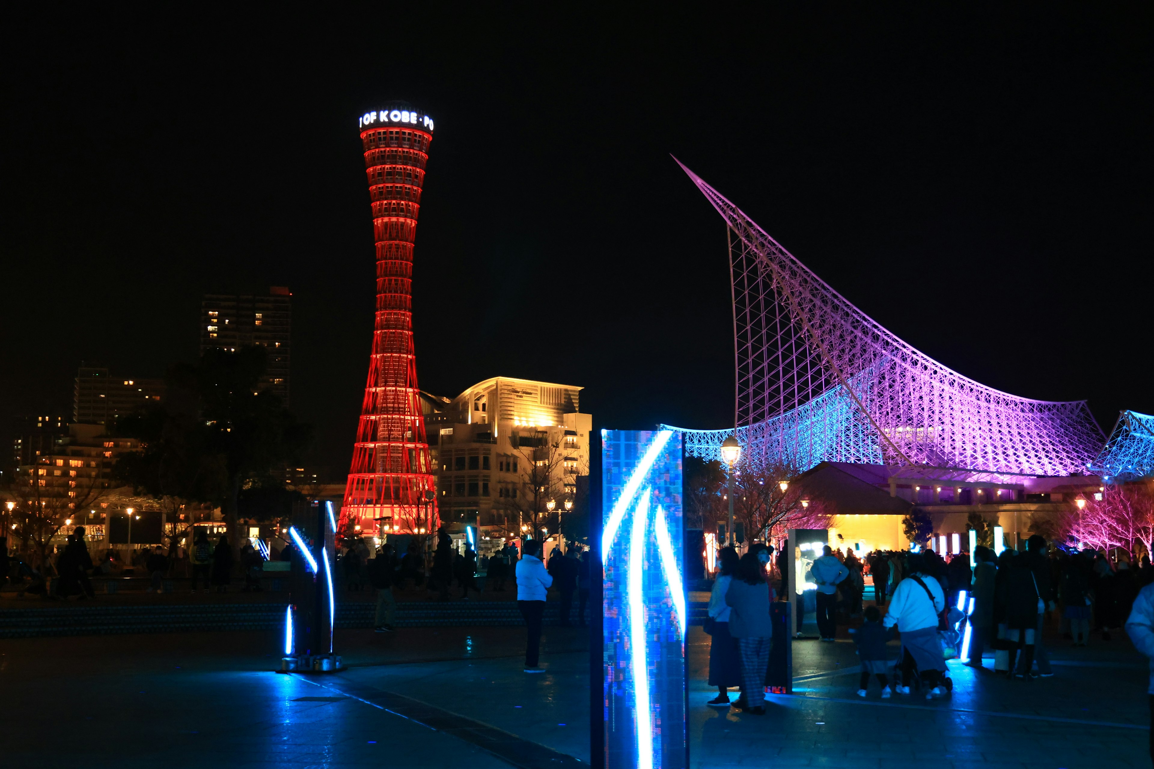 Pemandangan malam Pelabuhan Kobe dengan menara merah dan bangunan ungu