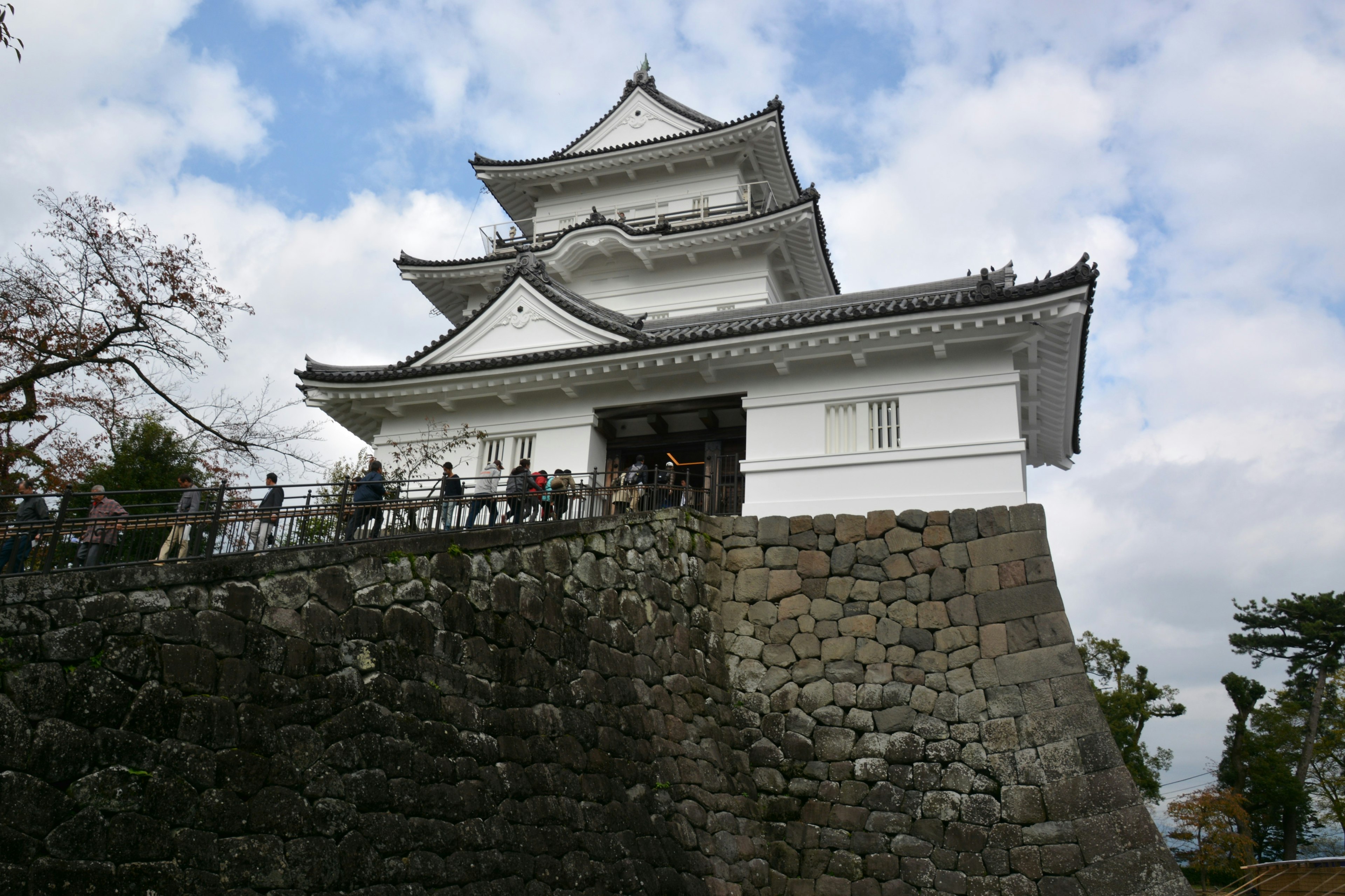 白色城堡在石牆上，遊客們在參觀