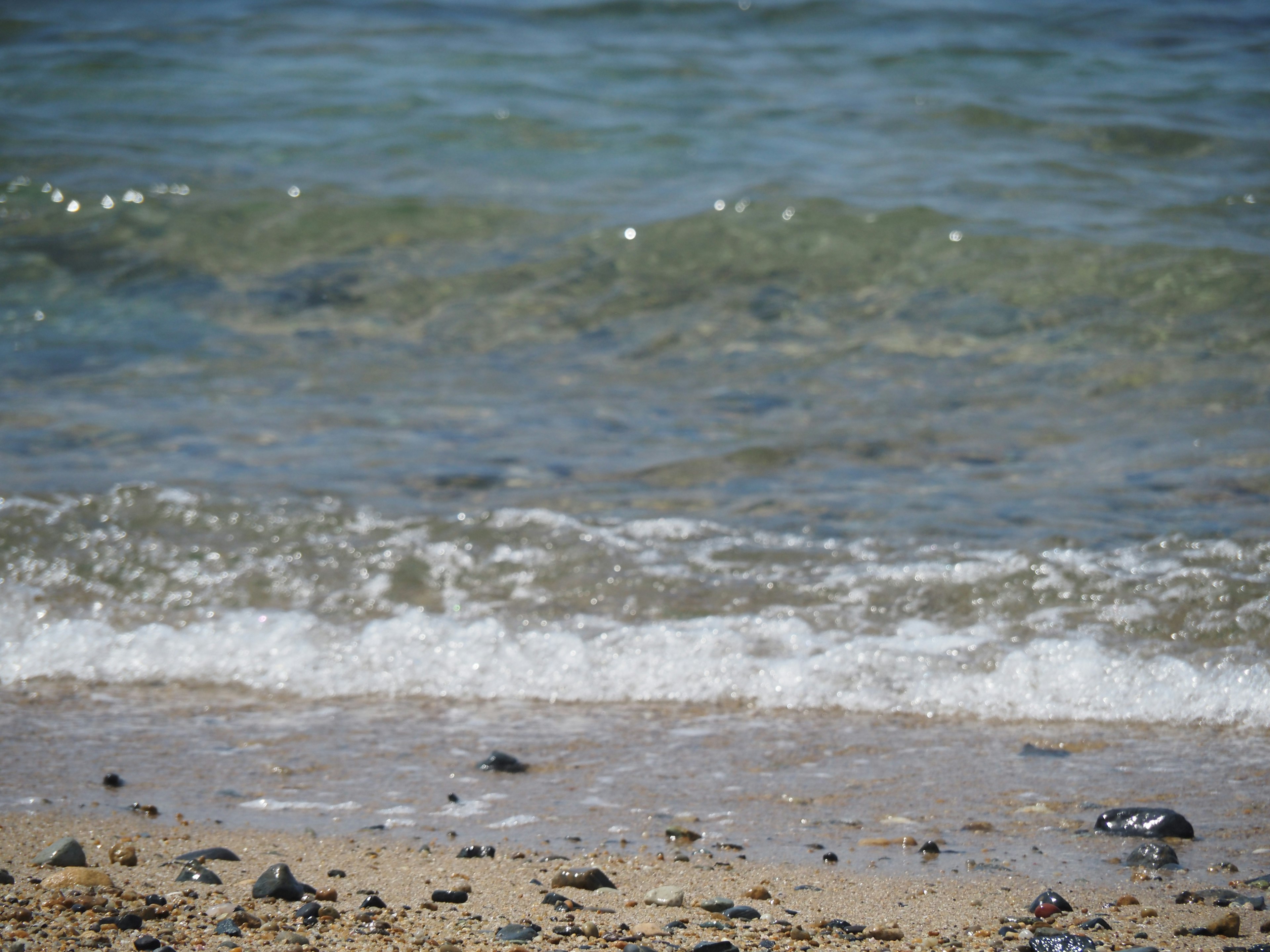 Onde che si infrangono su una spiaggia di sabbia con ciottoli