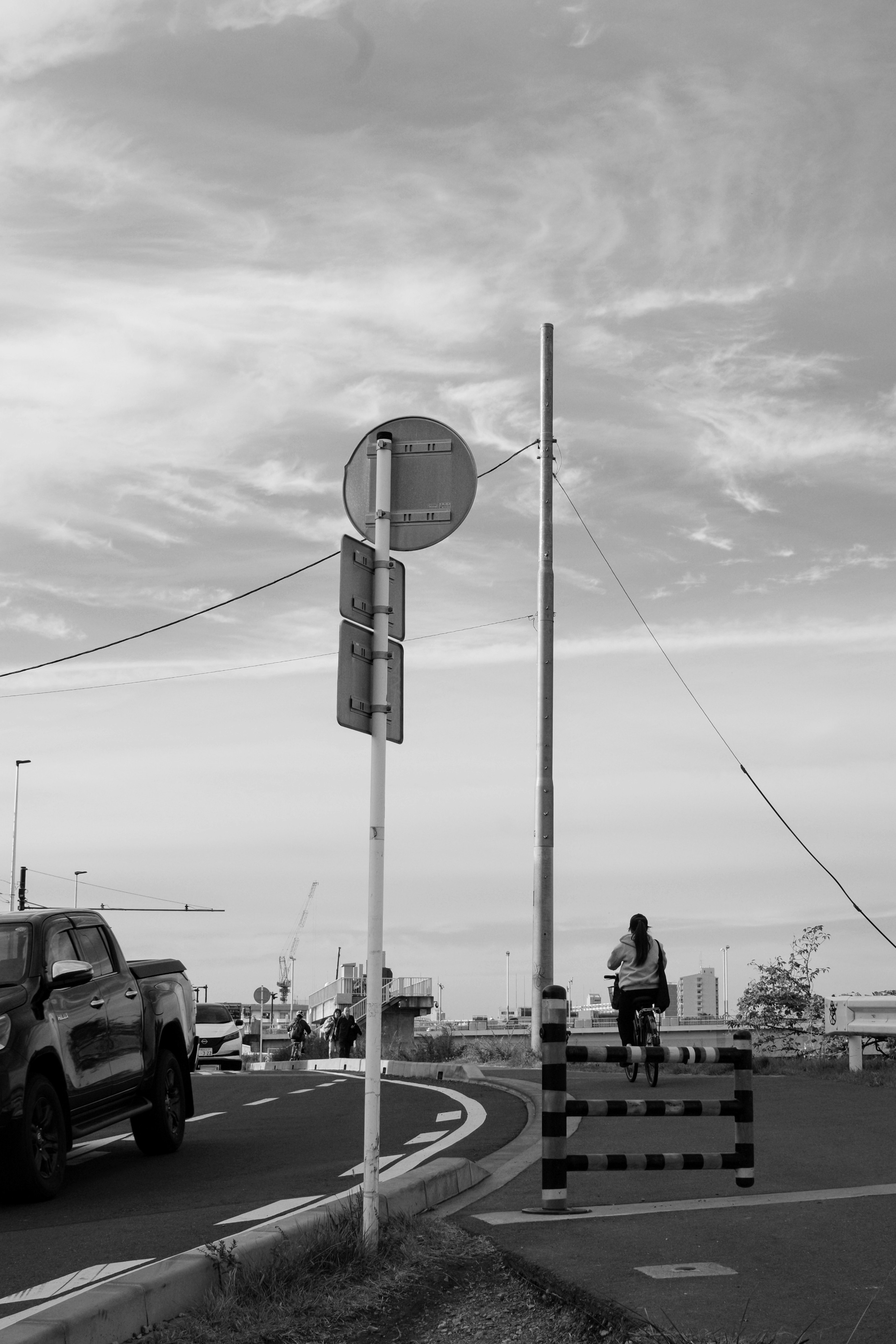 Schwarzweißfoto eines Verkehrsschilds an einer Kreuzung mit Baustellenabsperrung