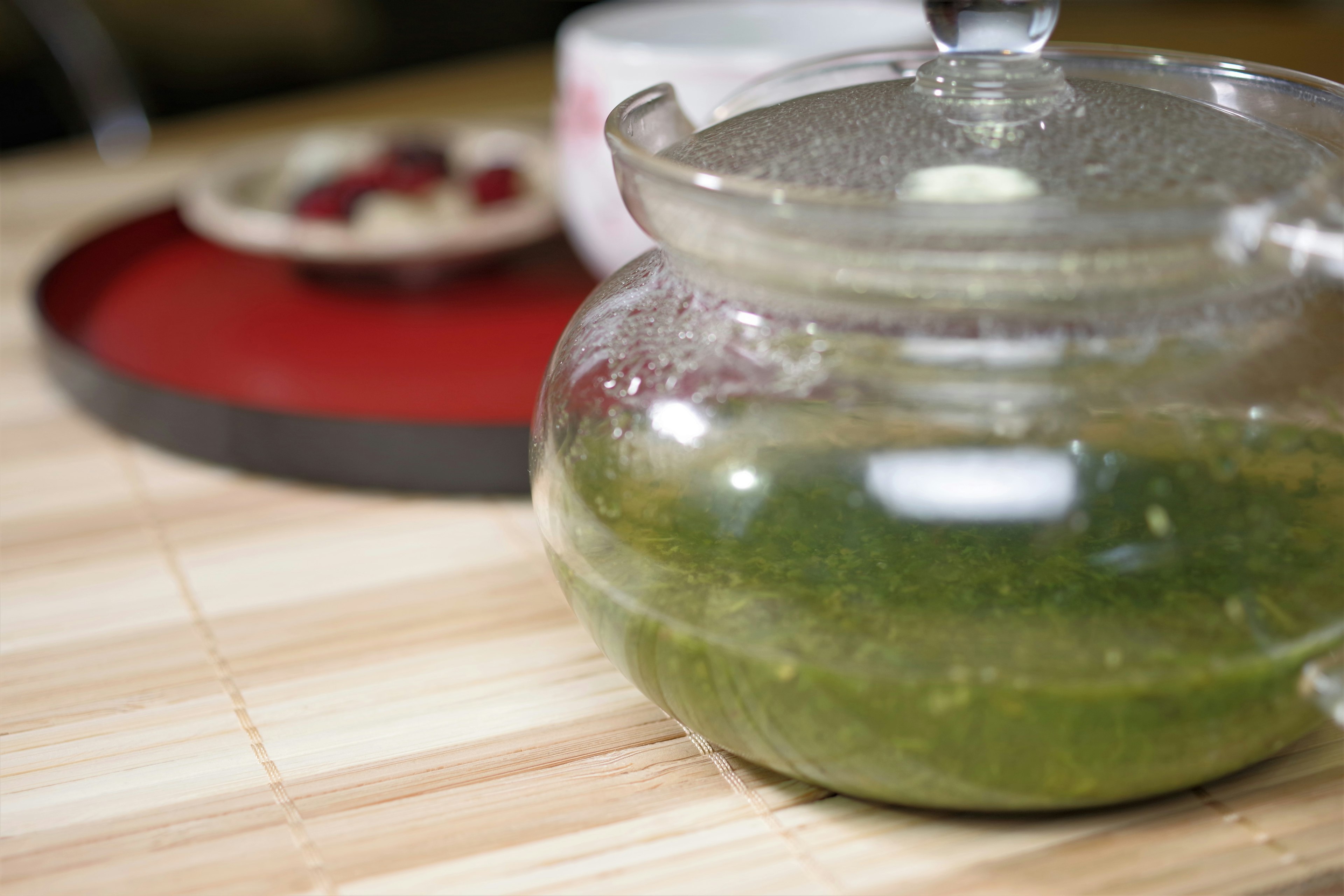 Théière transparente avec du thé vert sur une table en bois