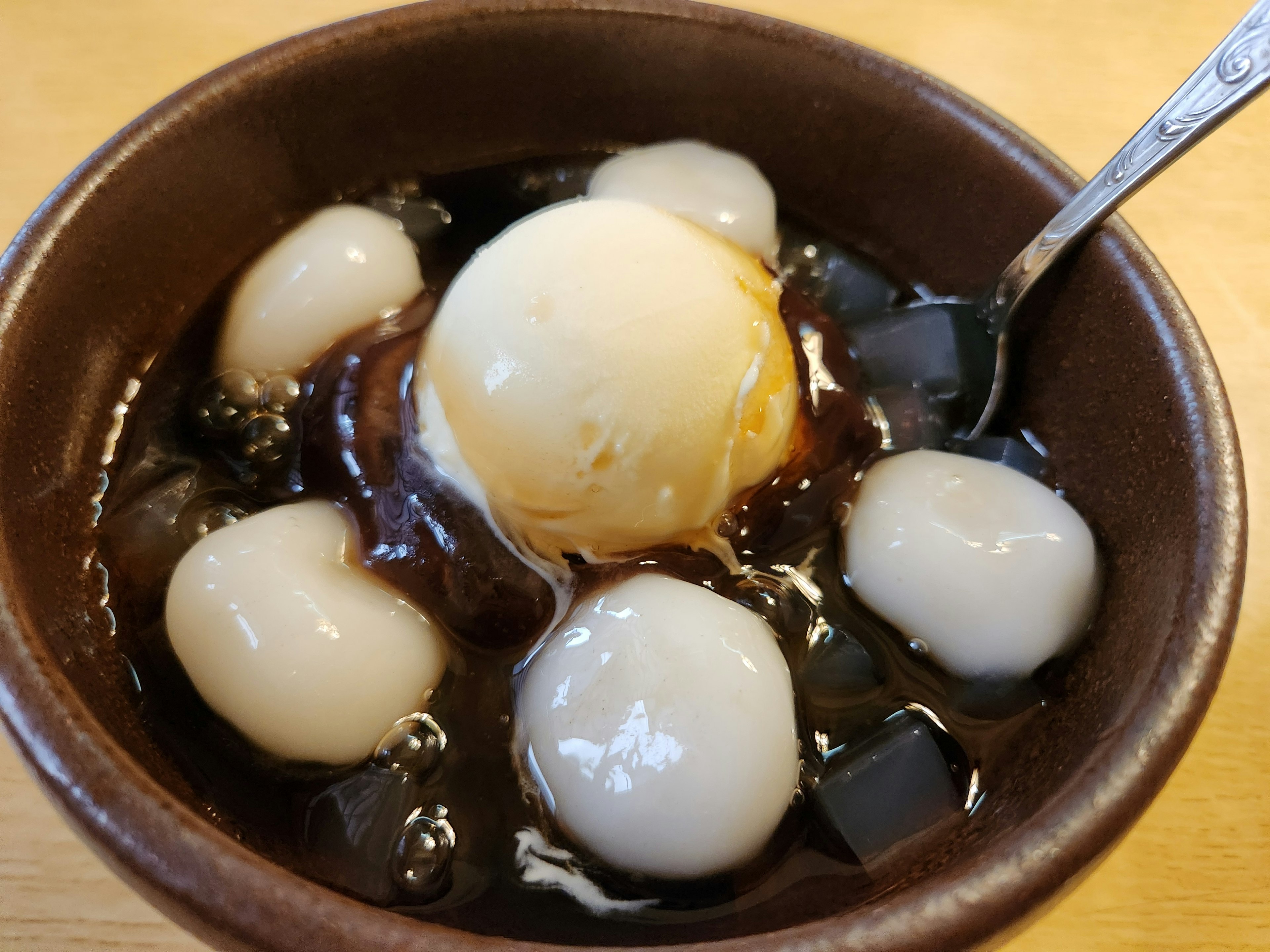 Dessert mit Klebreisbällchen und Eiscreme in dunklem Sirup