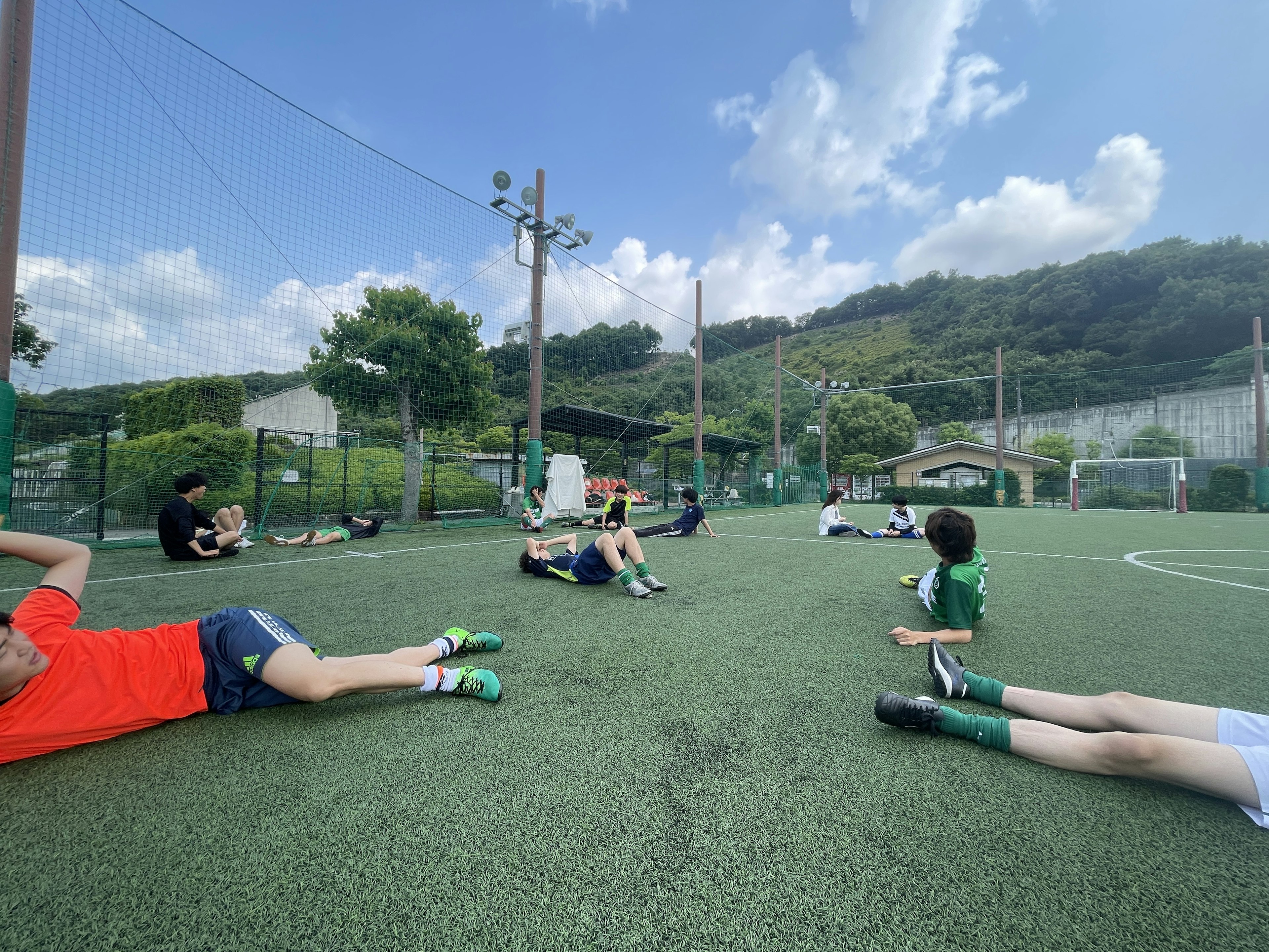 Bambini che si allungano su un campo da calcio sotto un cielo blu e su erba verde