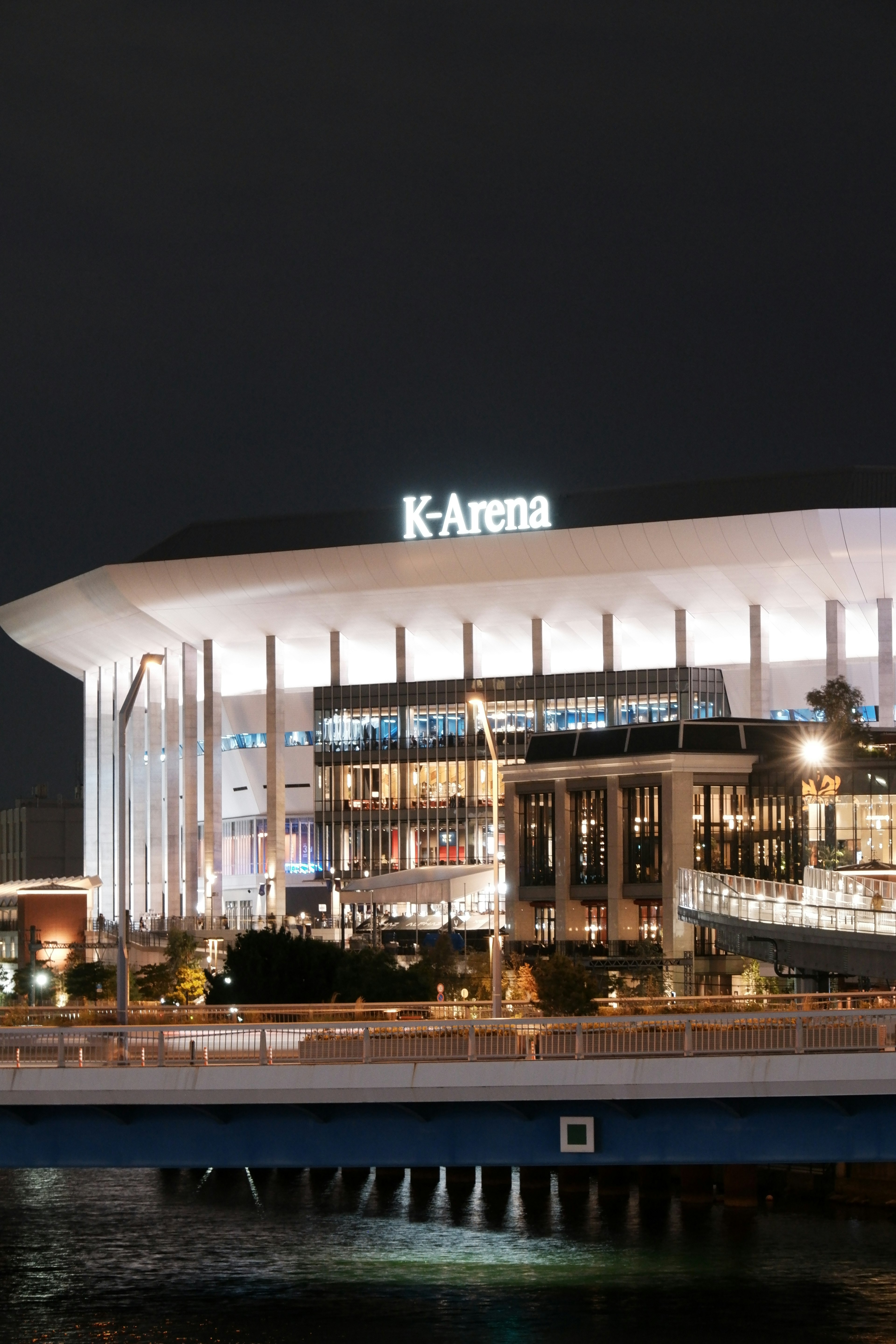 Vista nocturna del K-Arena con luces brillantes y arquitectura moderna