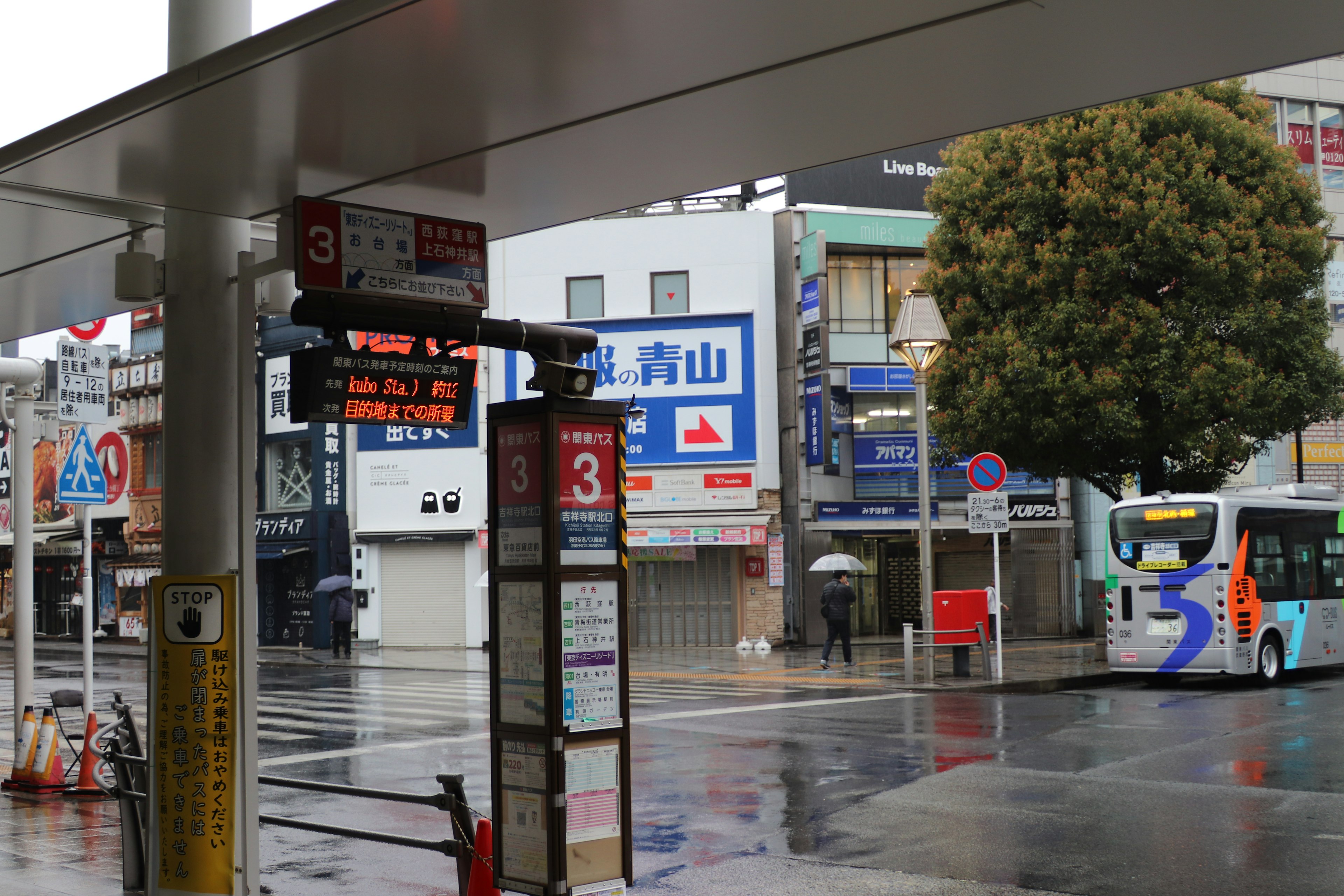 Bus stop scene on a rainy day with visible bus destination sign