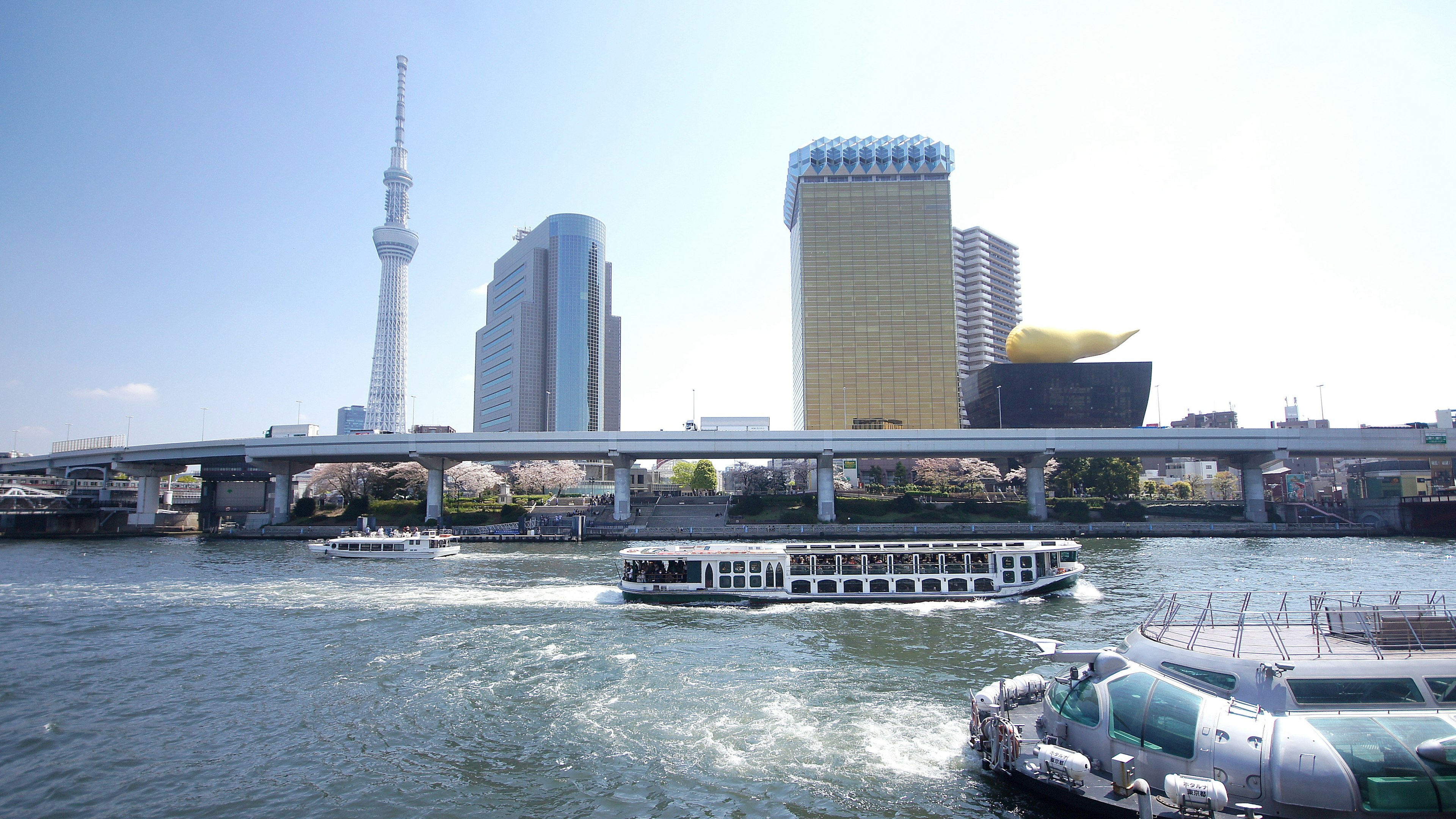 Autobús acuático navegando por el río con la Tokyo Skytree y edificios modernos al fondo