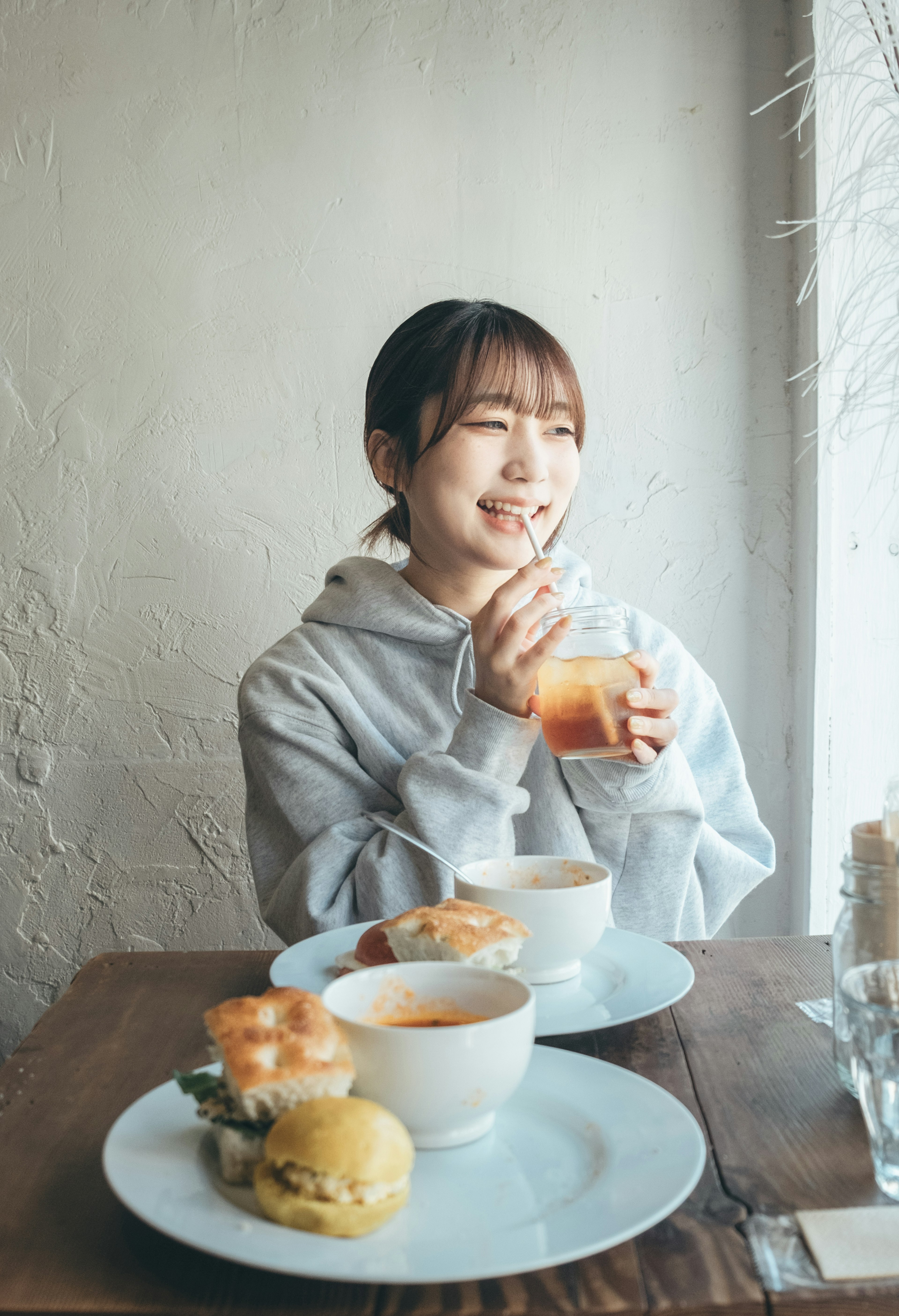 Mujer disfrutando de una bebida en un café con platos apetitosos